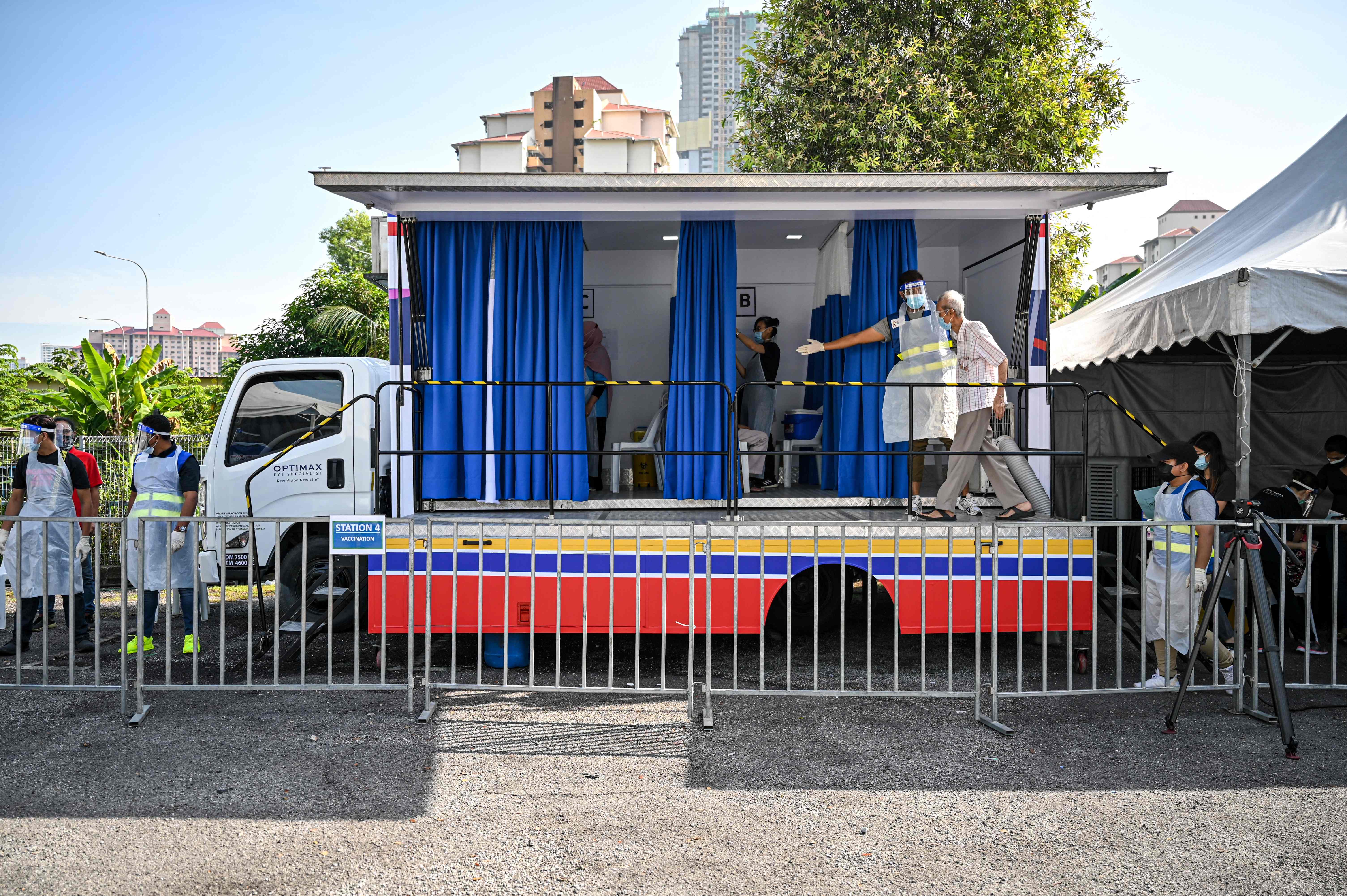 Seorang relawan membantu seorang warga lansia menuju lokasi vaksinasi covid-19 di Kuala Lumpur, Malaysia.