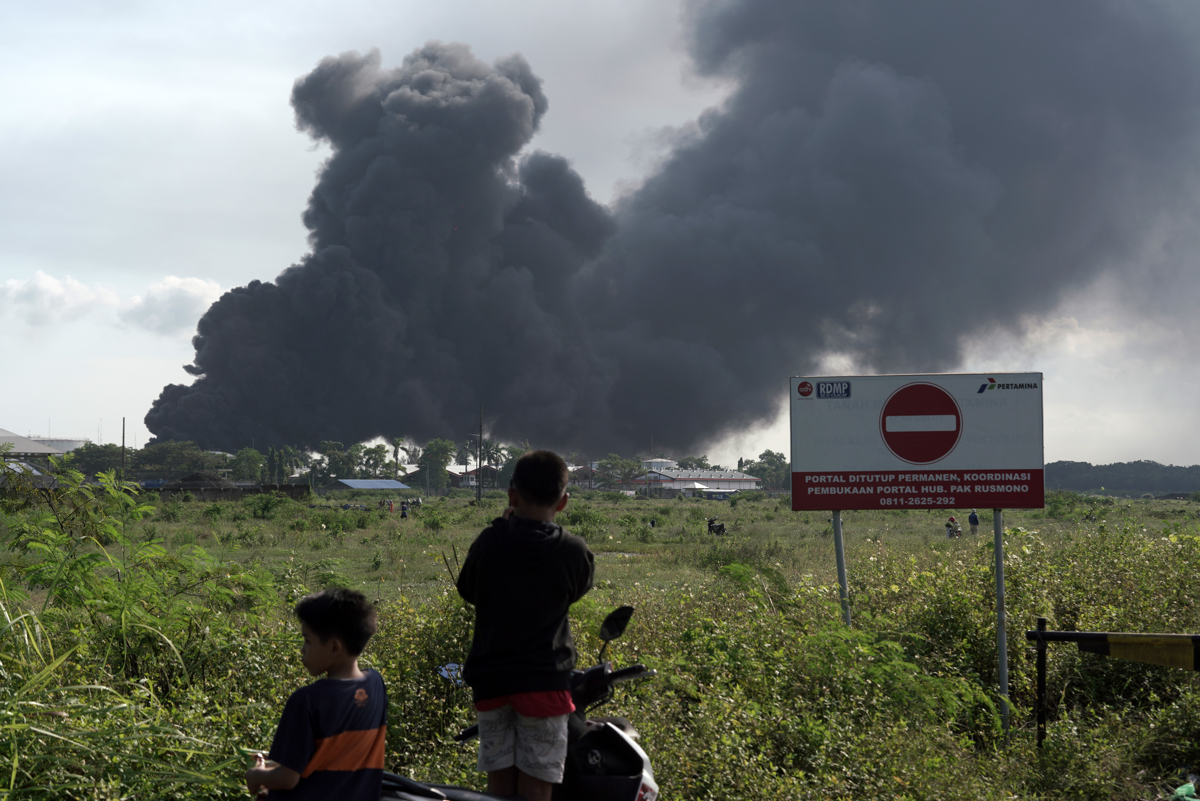 Warga menyaksikan kepulan asap dari kebakaran di area Kilang Cilacap milik Pertamina.