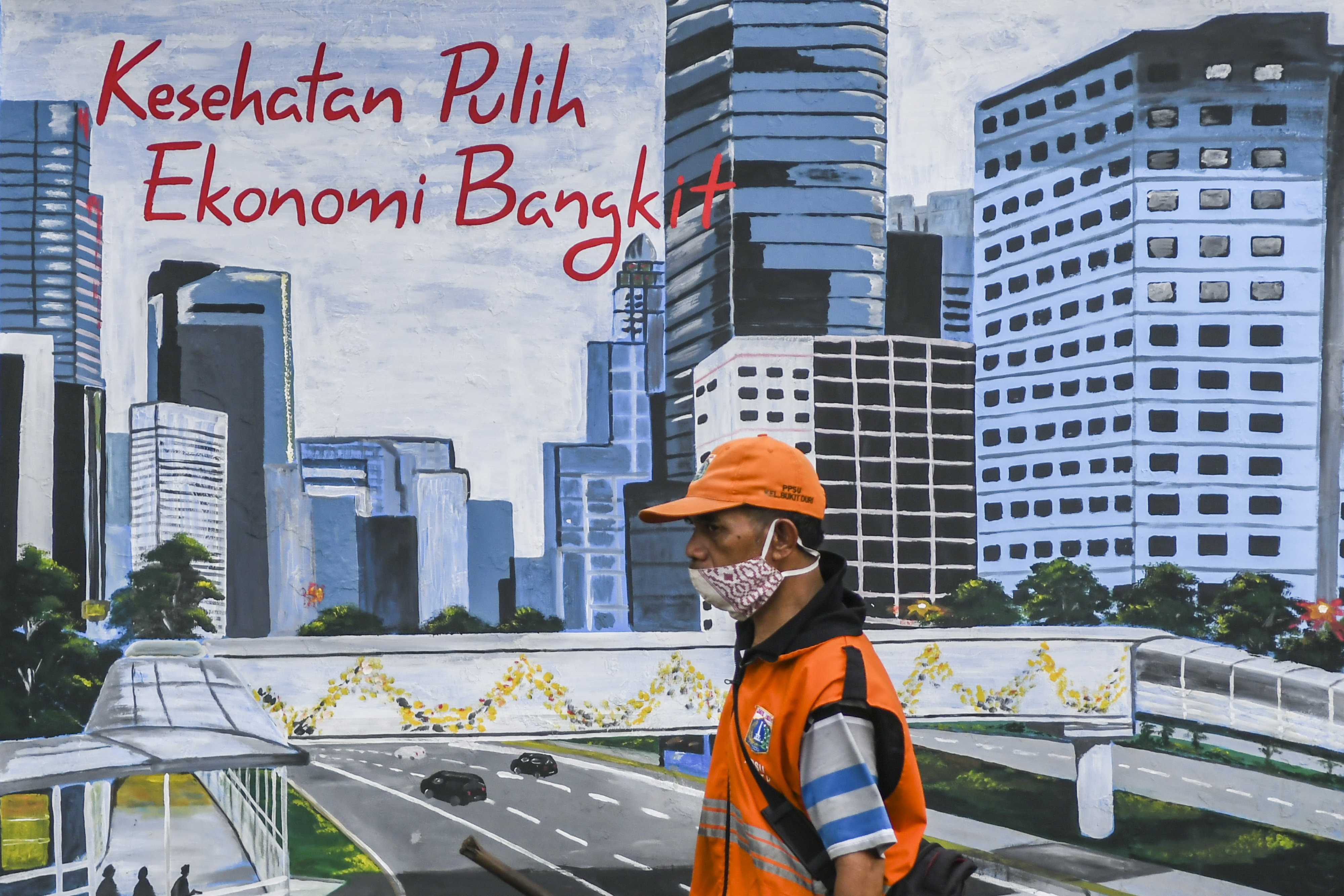 Petugas kebersihan melintas di depan mural tentang pandemi COVID-19 di Kawasan Tebet, Jakarta