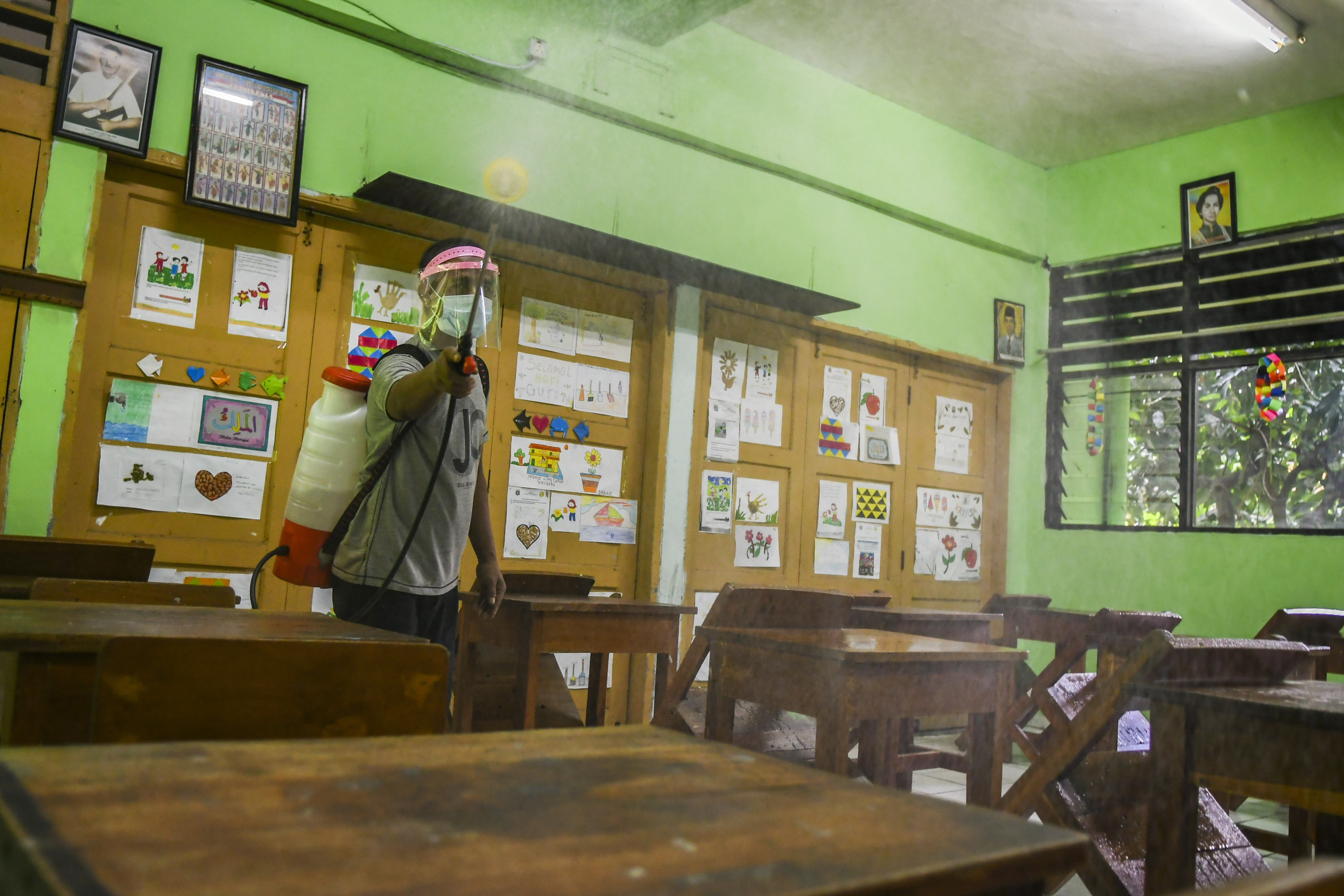 Petugas menyemprotkan disinfektan di ruang kelas SD Kenari 08 Pagi, Jakarta.