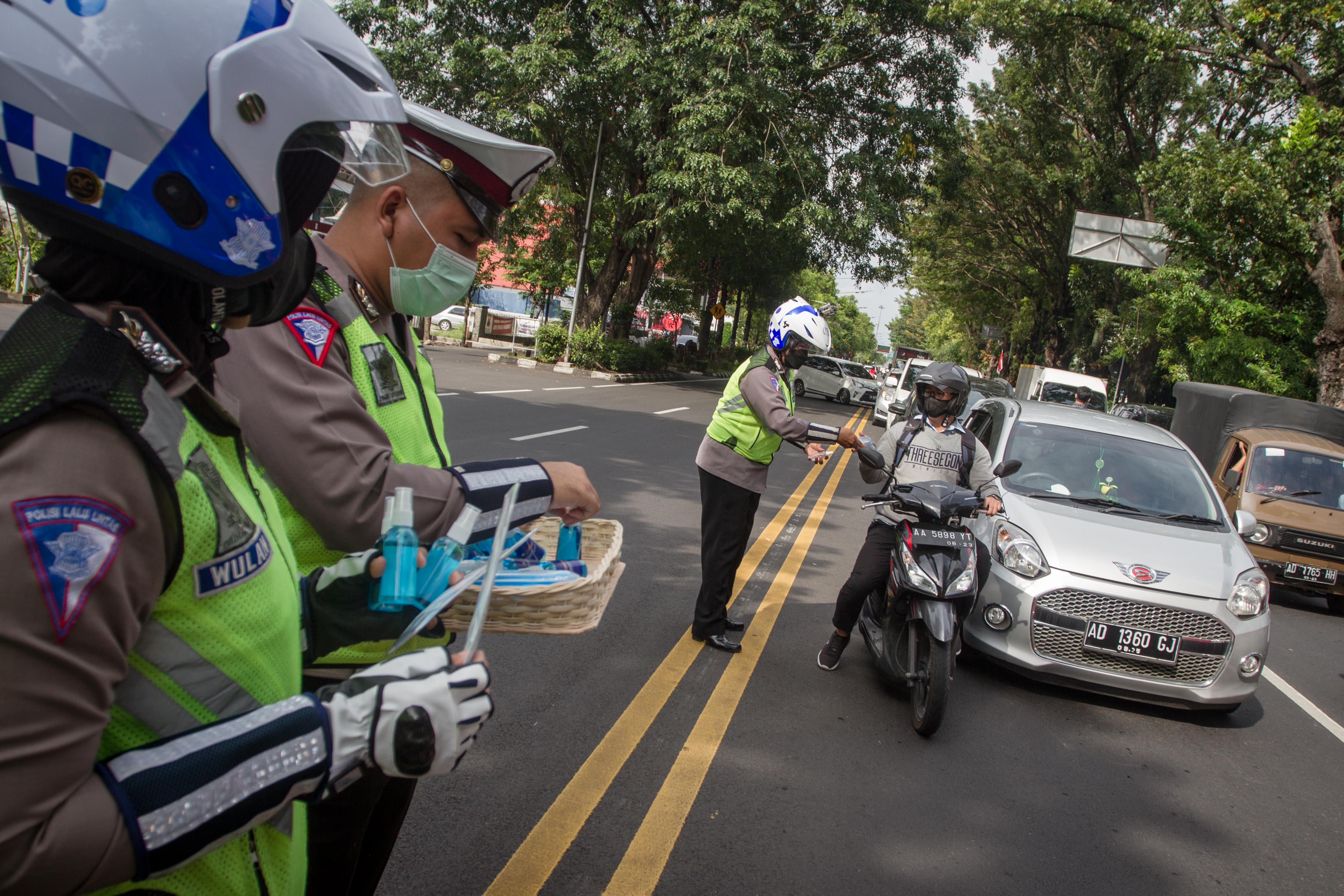 Petugas kepolisian di Solo membagikan masker dan hand sanitizer kepada pengendara.
