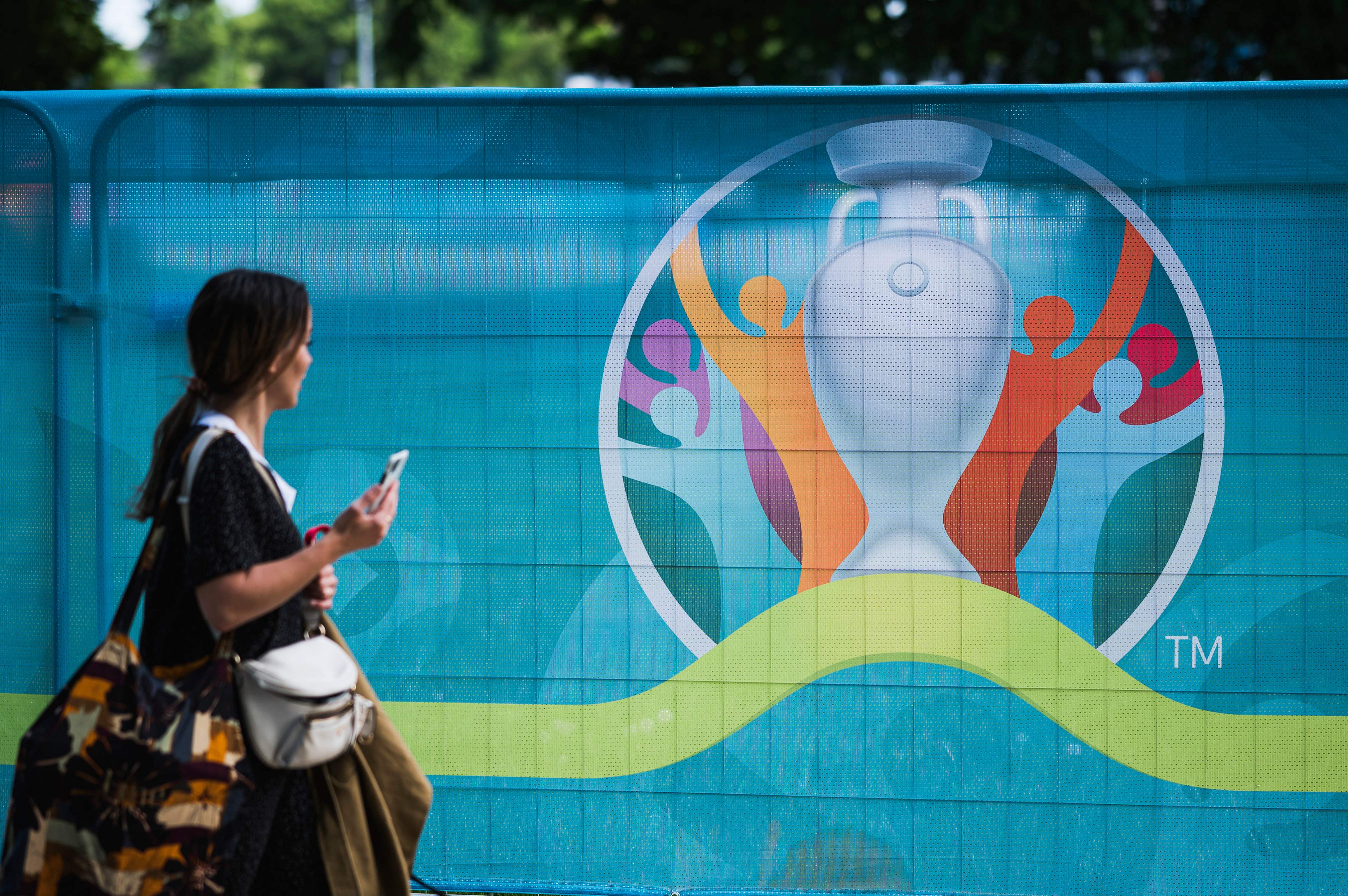 Seorang warga melintas di depan logo Piala Eropa 2020 di Copenhagen, Denmark.