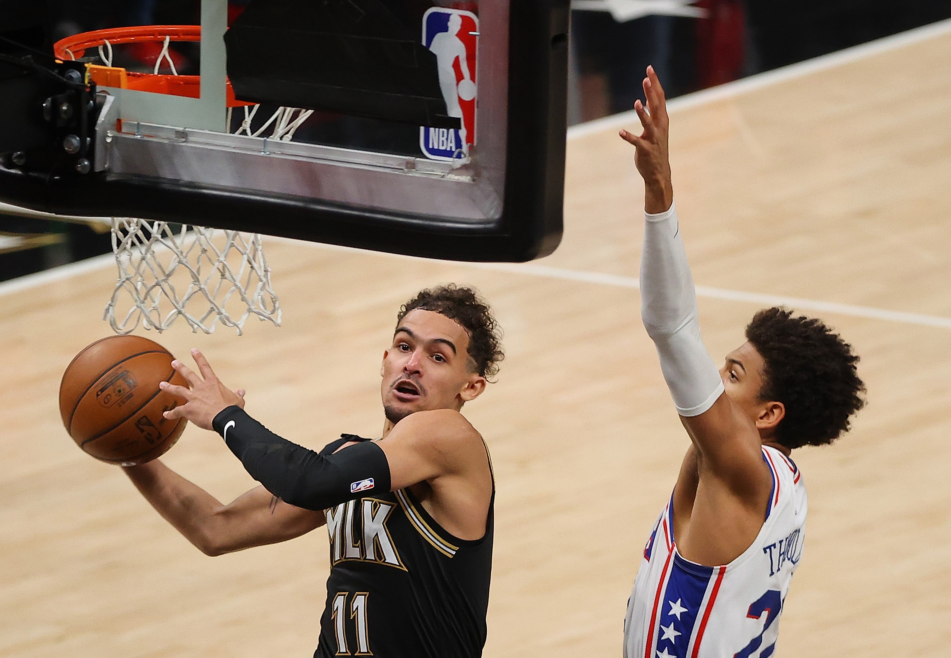 Pemain Atlanta Hawks Trae Young (kiri) siap melesakkan bola ke jaring dengan diganggu Matisse Thybulle dari Philadelphia 76ers. 