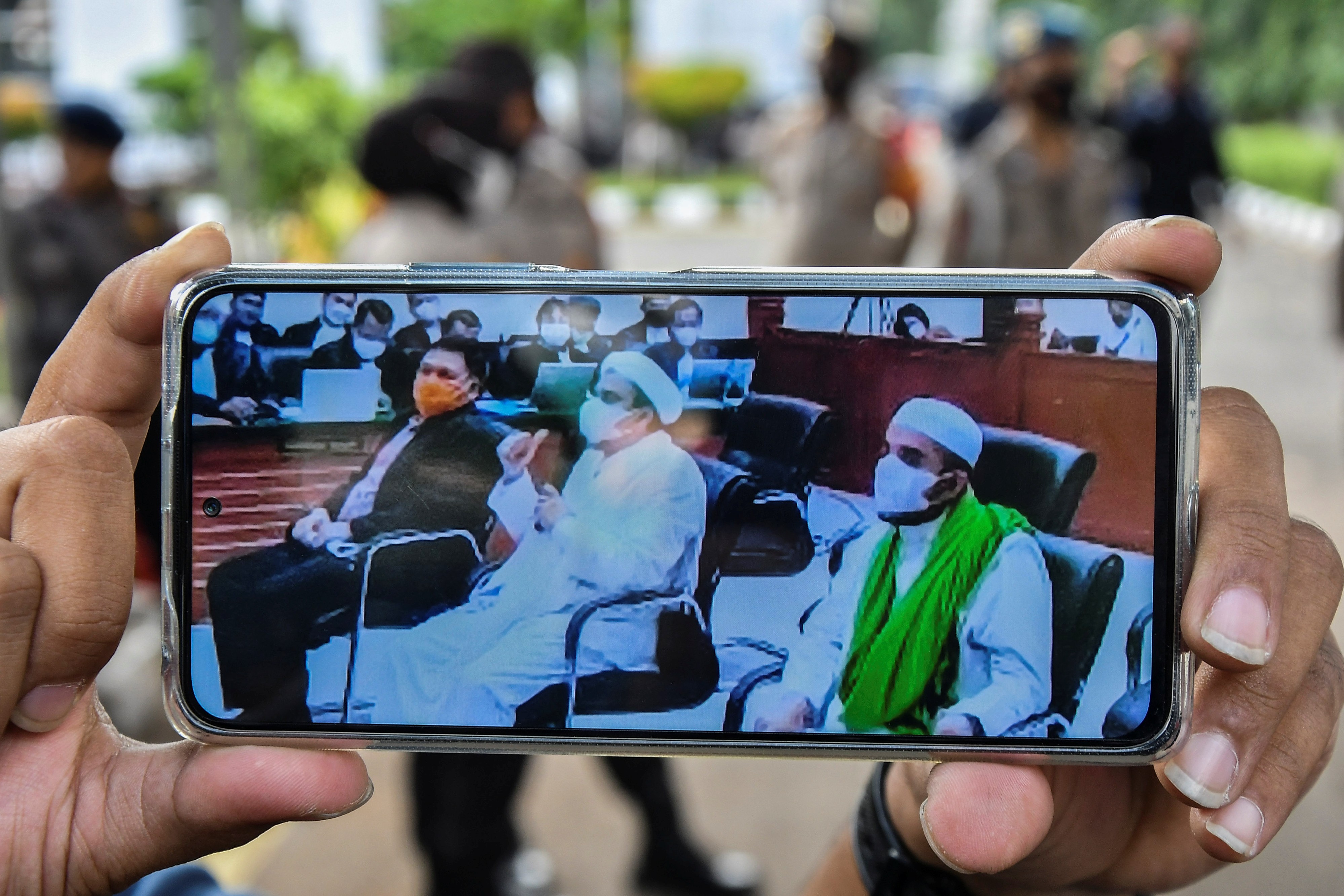 Layar telepon pintar menampilkan suasana sidang yang dihadiri Habib Rizieq Shihab (tengah) dan Direktur Rumah Sakit UMMI Andi Tatat (kiri).