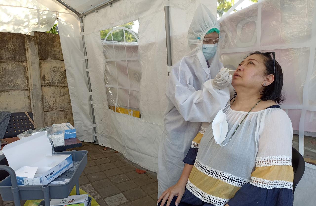 Seorang tenaga kesehatan melakukan tes swab antigen pada warga.