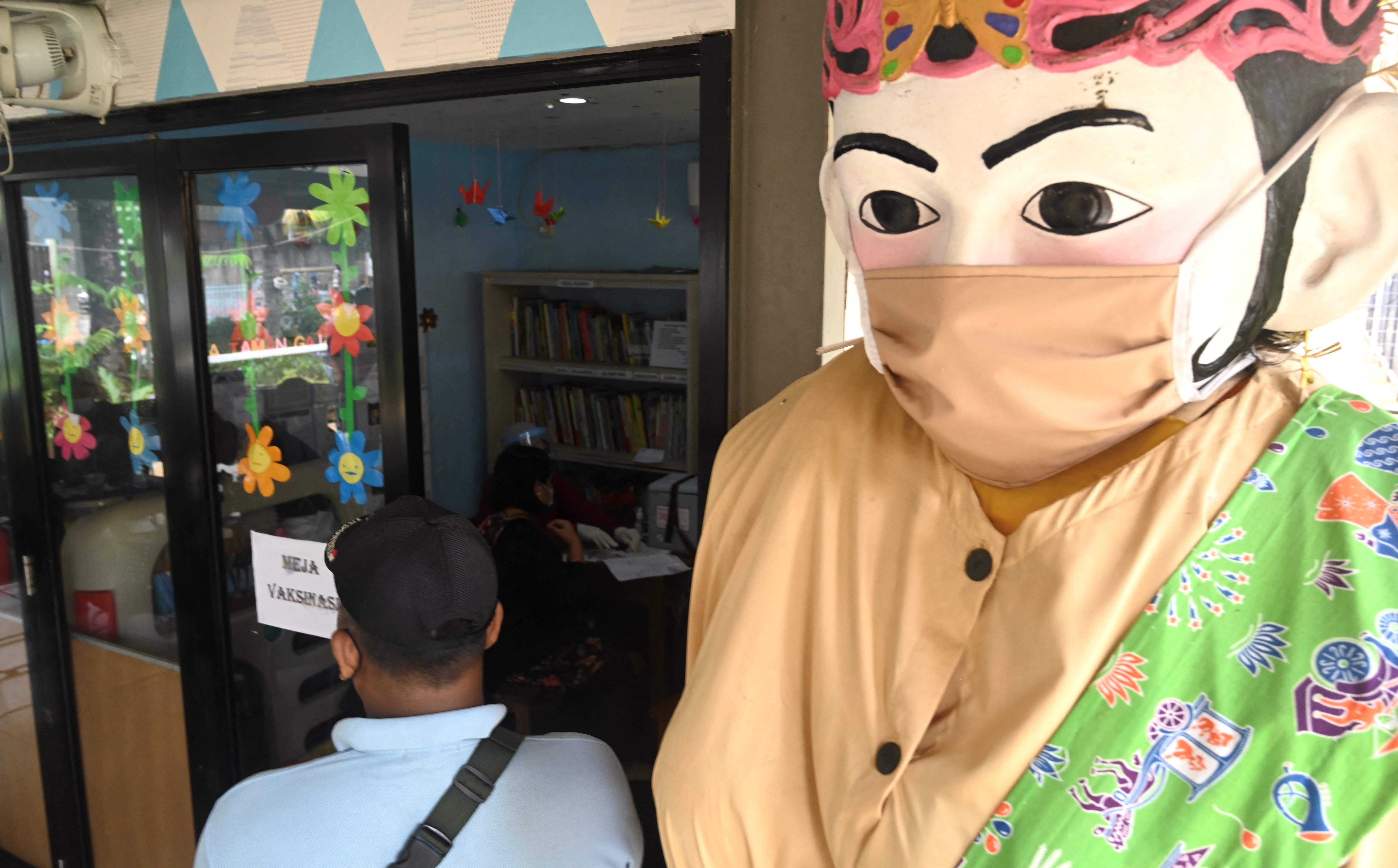 Sebuiah ondel-ondel yang mengenakan masker menghiasi sebuah pusat vaksinasi covid-19 di Jakarta.