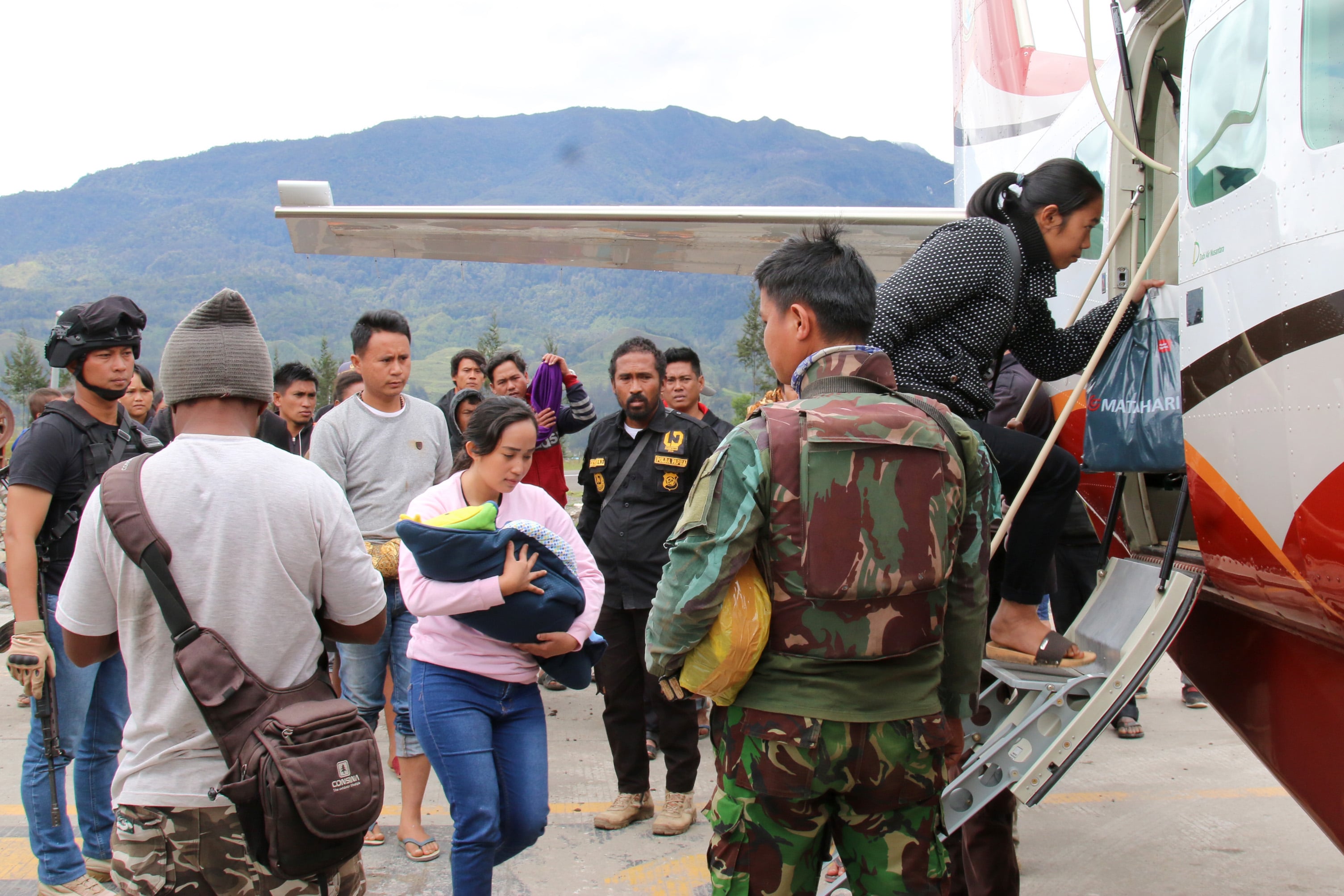 Warga memasuki pesawat dengan penjagaan aparat keamanan di Bandara Ilaga, Kabupaten Puncak, Papua, tahun 2019