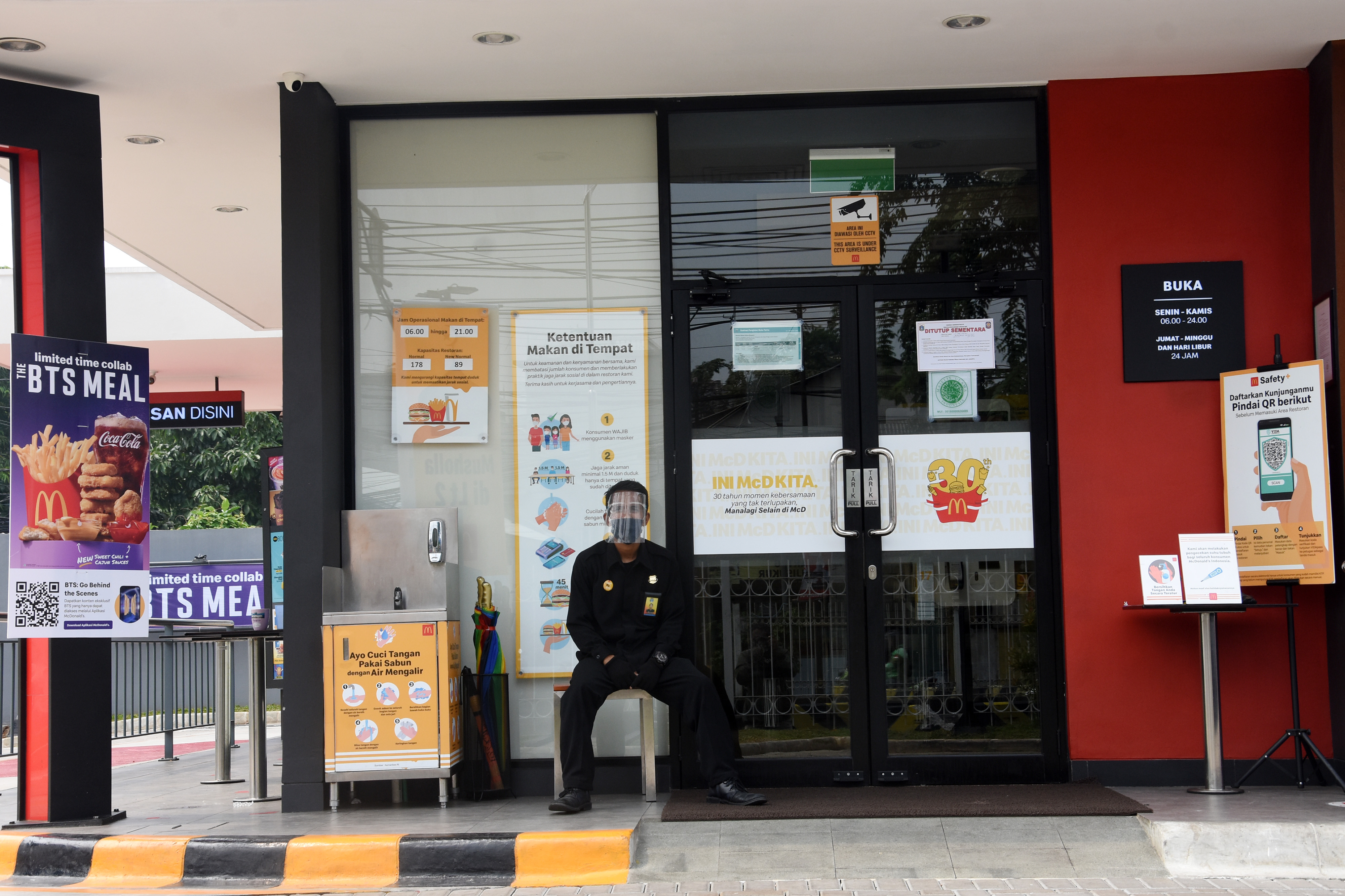 Petugas keamanan berjaga di salah satu gerai restoran cepat saji McDonald's yang ditutup sementara di Jalan Tambak, Jakarta