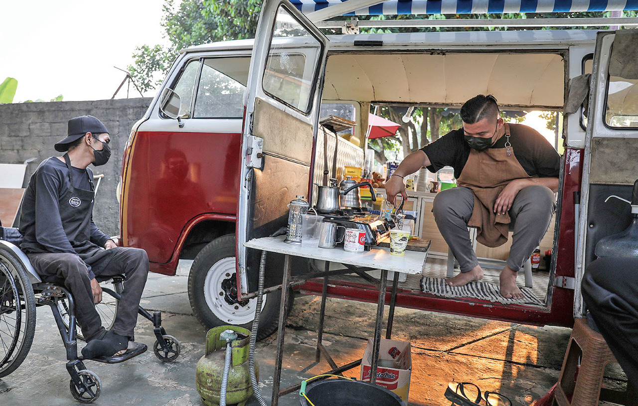 Barista Kito Rato Cafe, Rahmad (kanan) tengah meracik kopi dengan dibantu Rizky (berkursi roda) di Kito Rato Cafe, Pamulang, Tangsel.