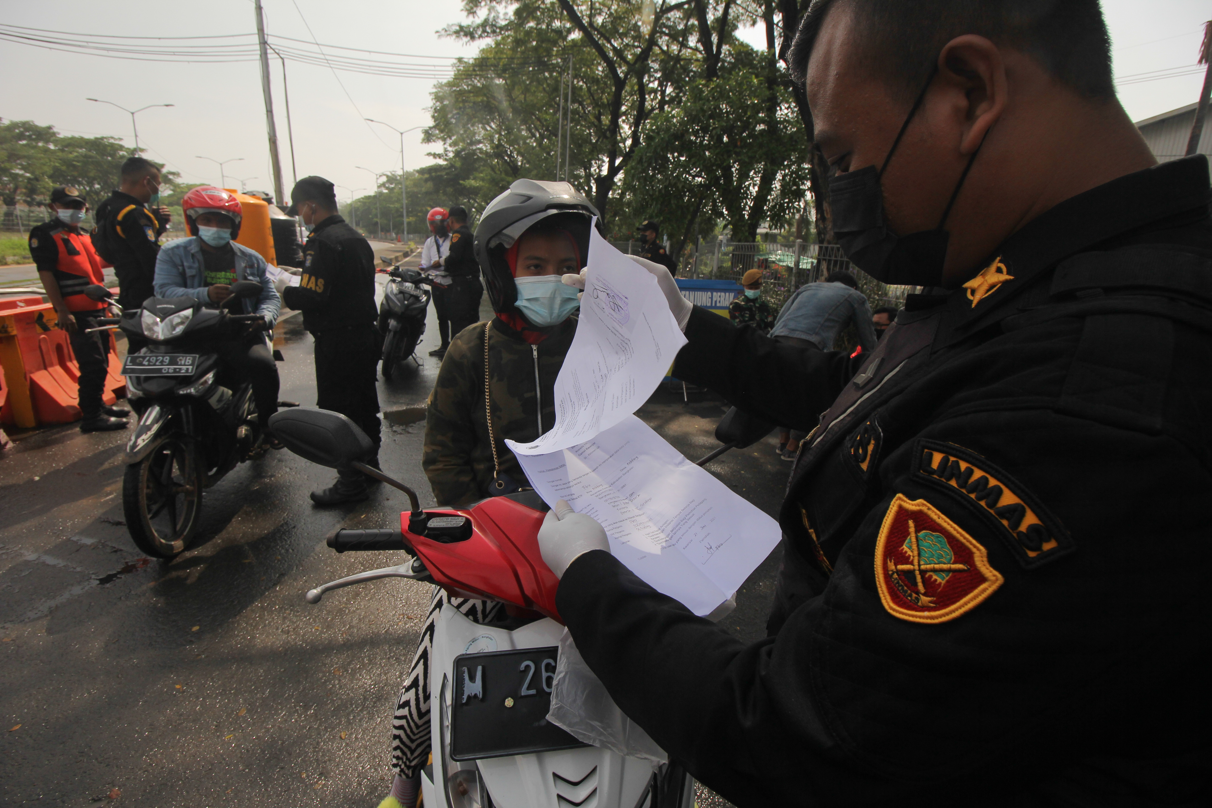 Petugas memeriksa dokumen Surat Izin Keluar Masuk (SIKM) milik warga yang akan masuk ke Surabaya di akses keluar Jembatan Suramadu