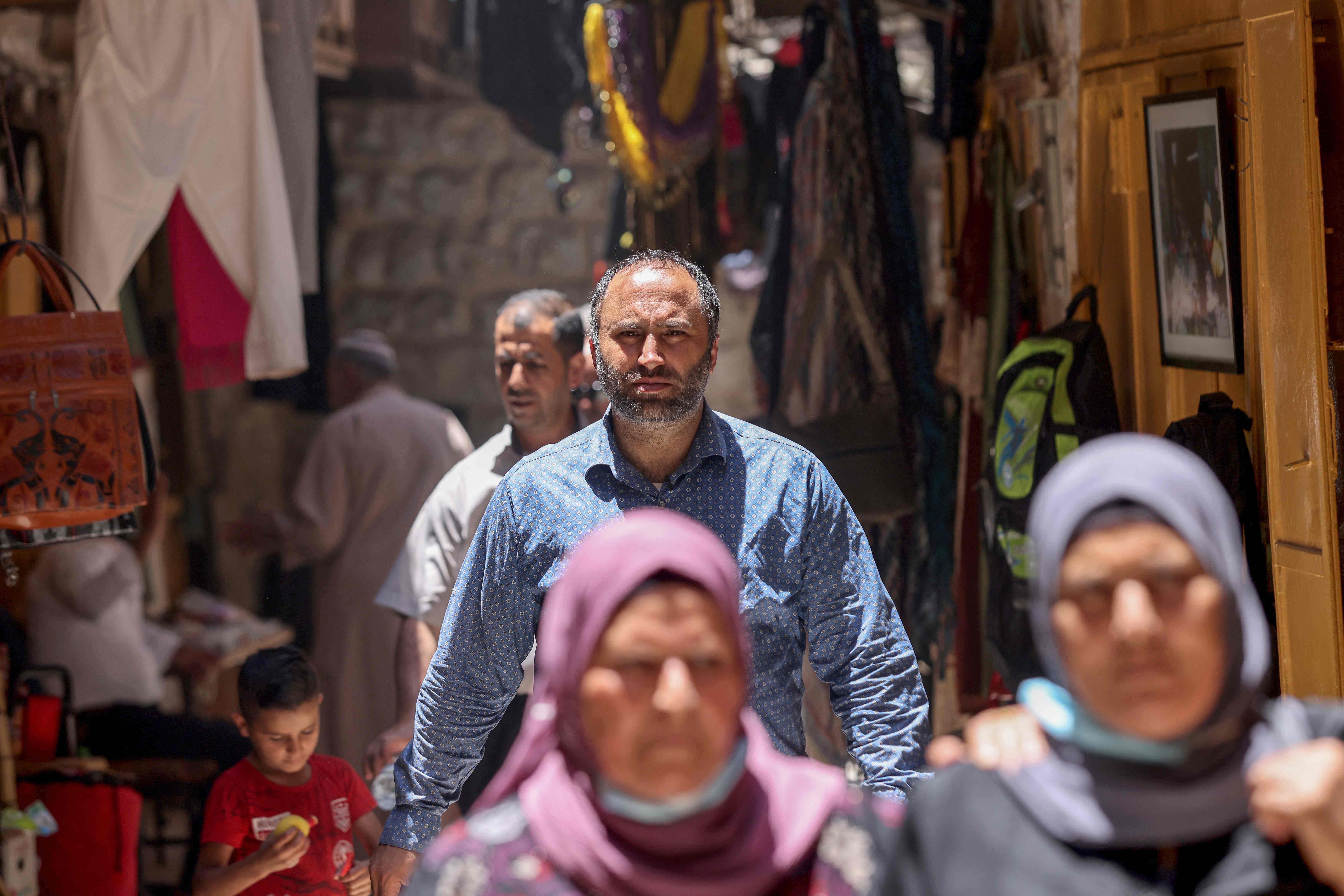 Issa Amro (kemeja biru) tengah berjalan di pasar, kota tua Hebron, Tepi Barat yang diduduki Israel, Minggu (27/6). 
