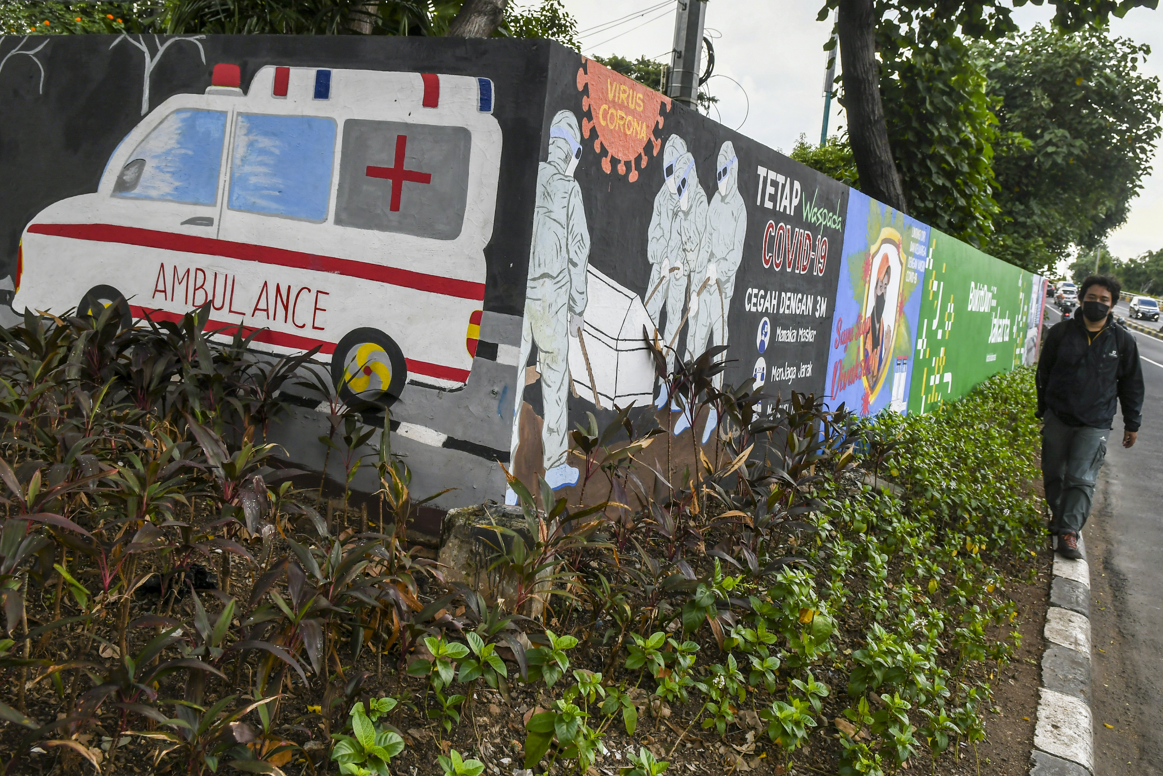  Warga melintas di depan mural tentang pandemi COVID-19 di Kawasan Tebet, Jakarta.