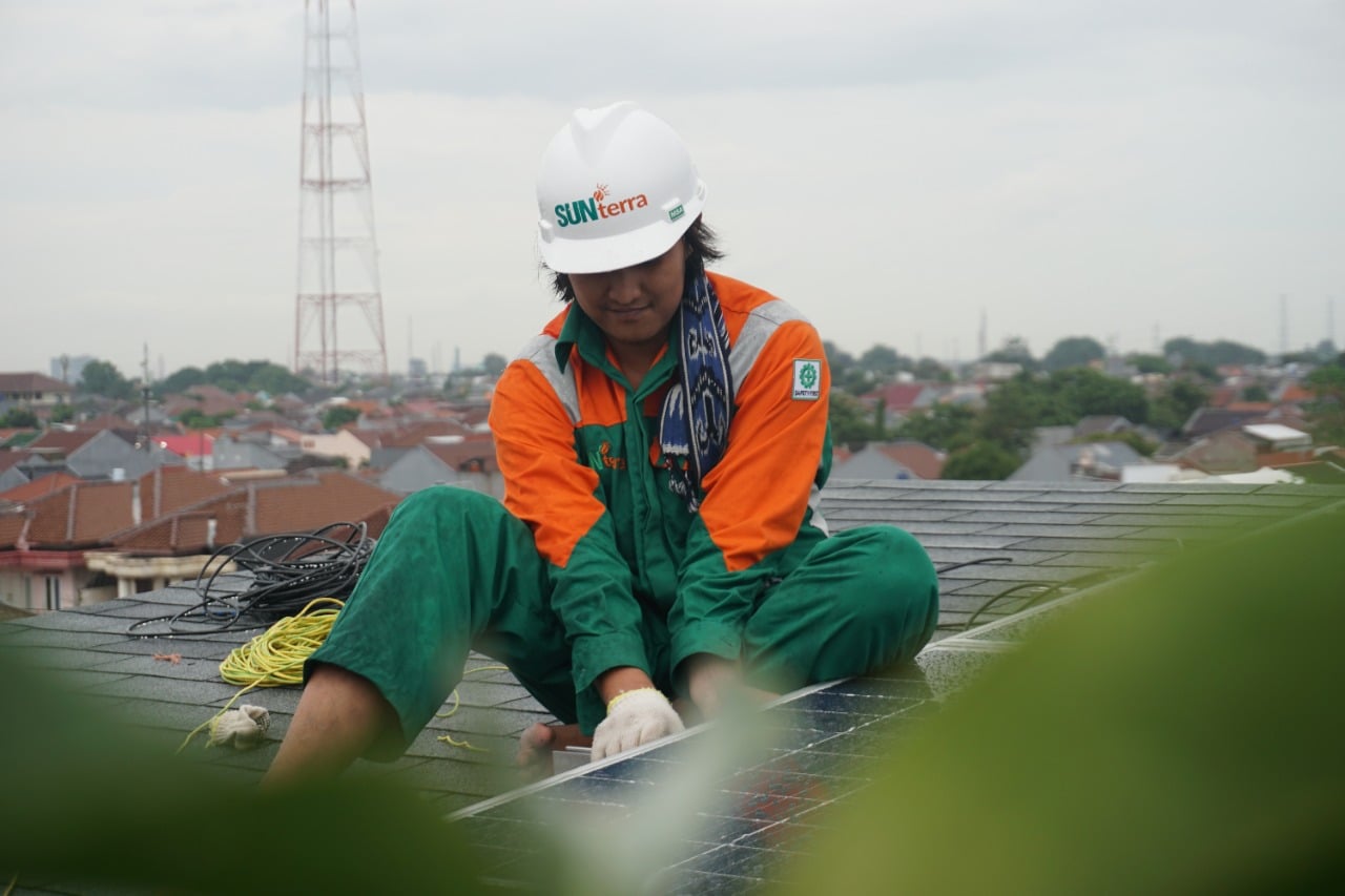 Pekerja tengah memasang panel surya.