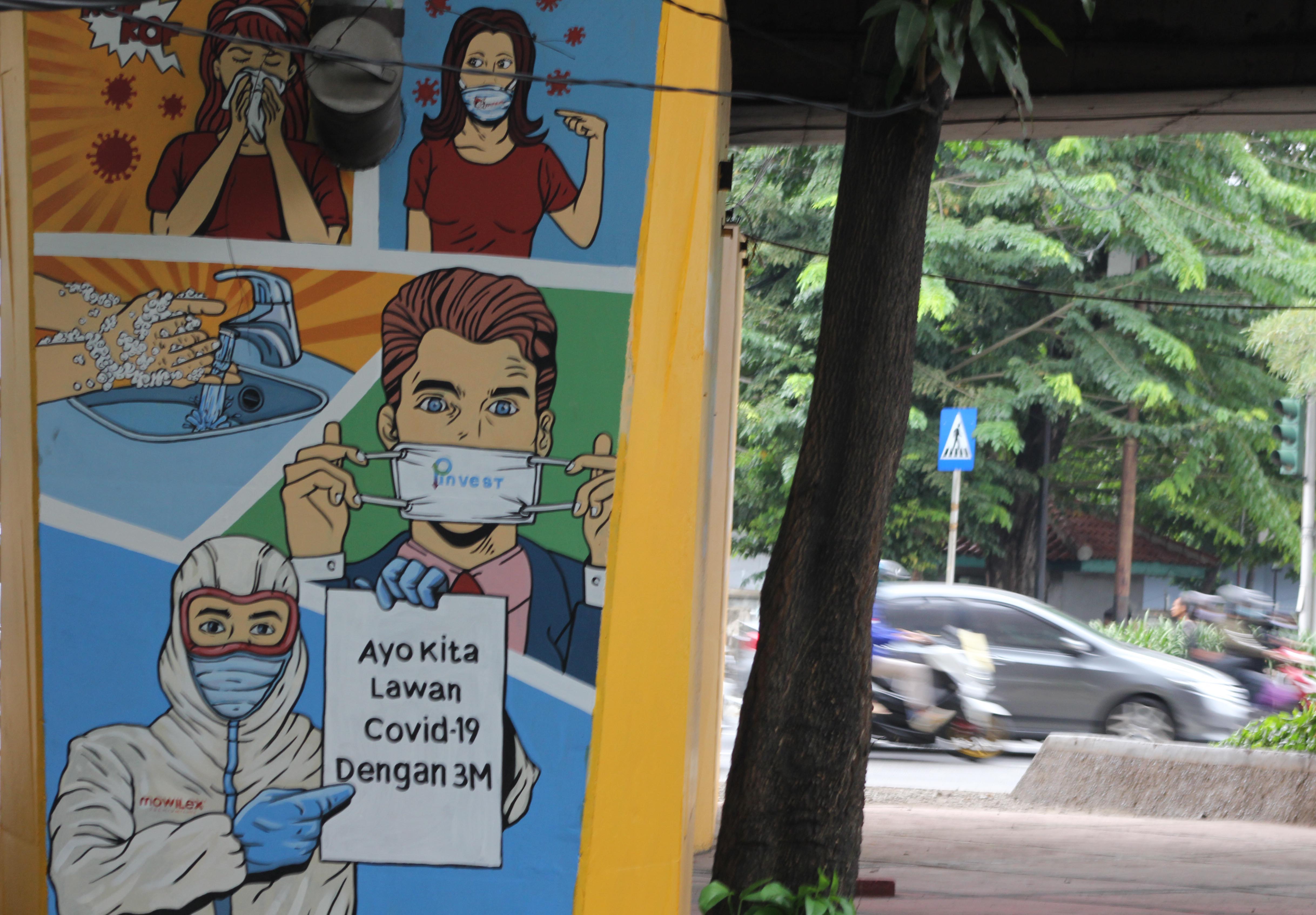 Pengendara melintas didepan Mural sosialisasi pencegahan penularan virus Covid-19 di Jakarta.