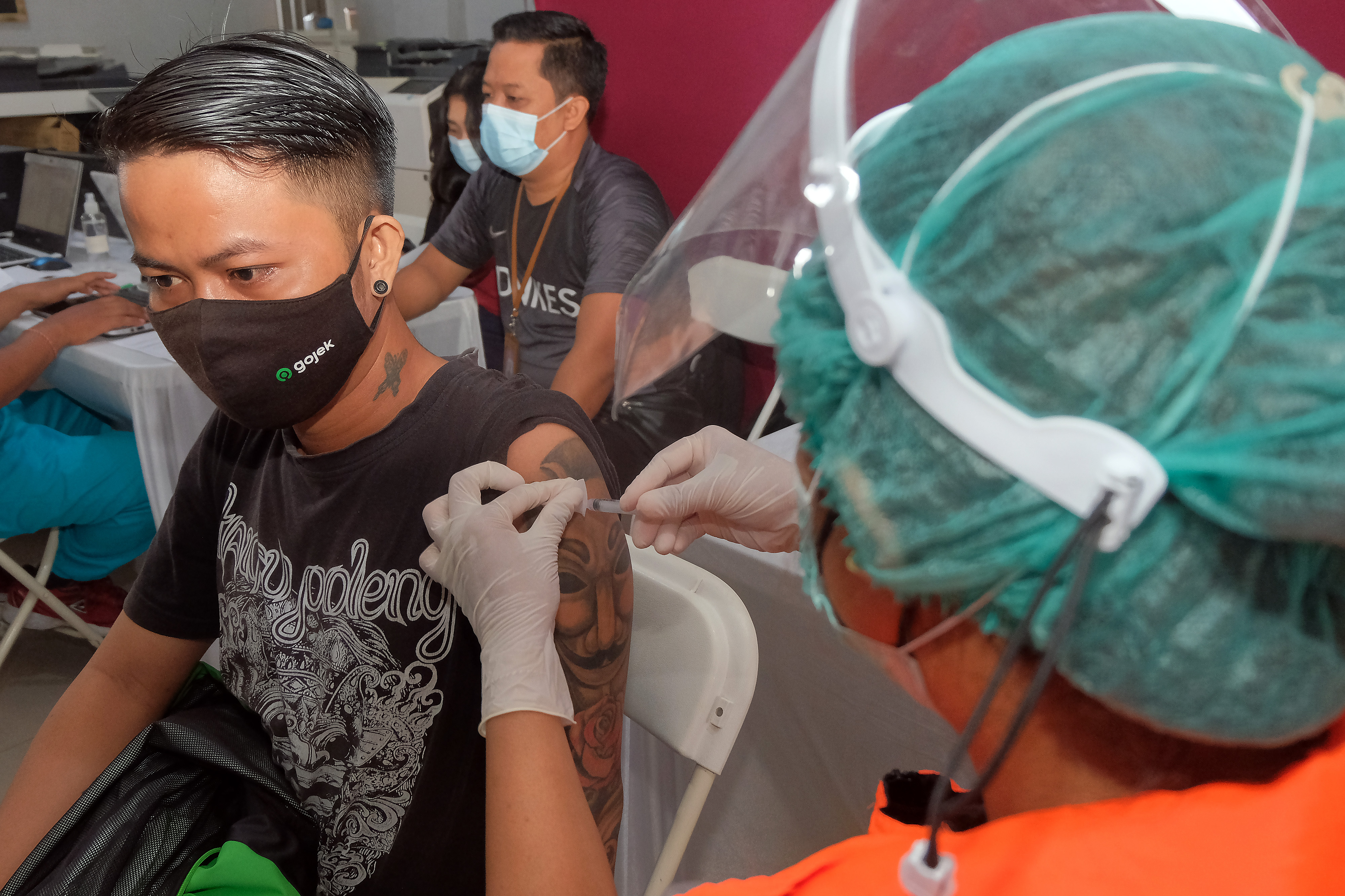 Petugas kesehatan menyuntikkan vaksin COVID-19 kepada pengemudi ojek online (ojol) di Denpasar, Bali, Sabtu (12/6).