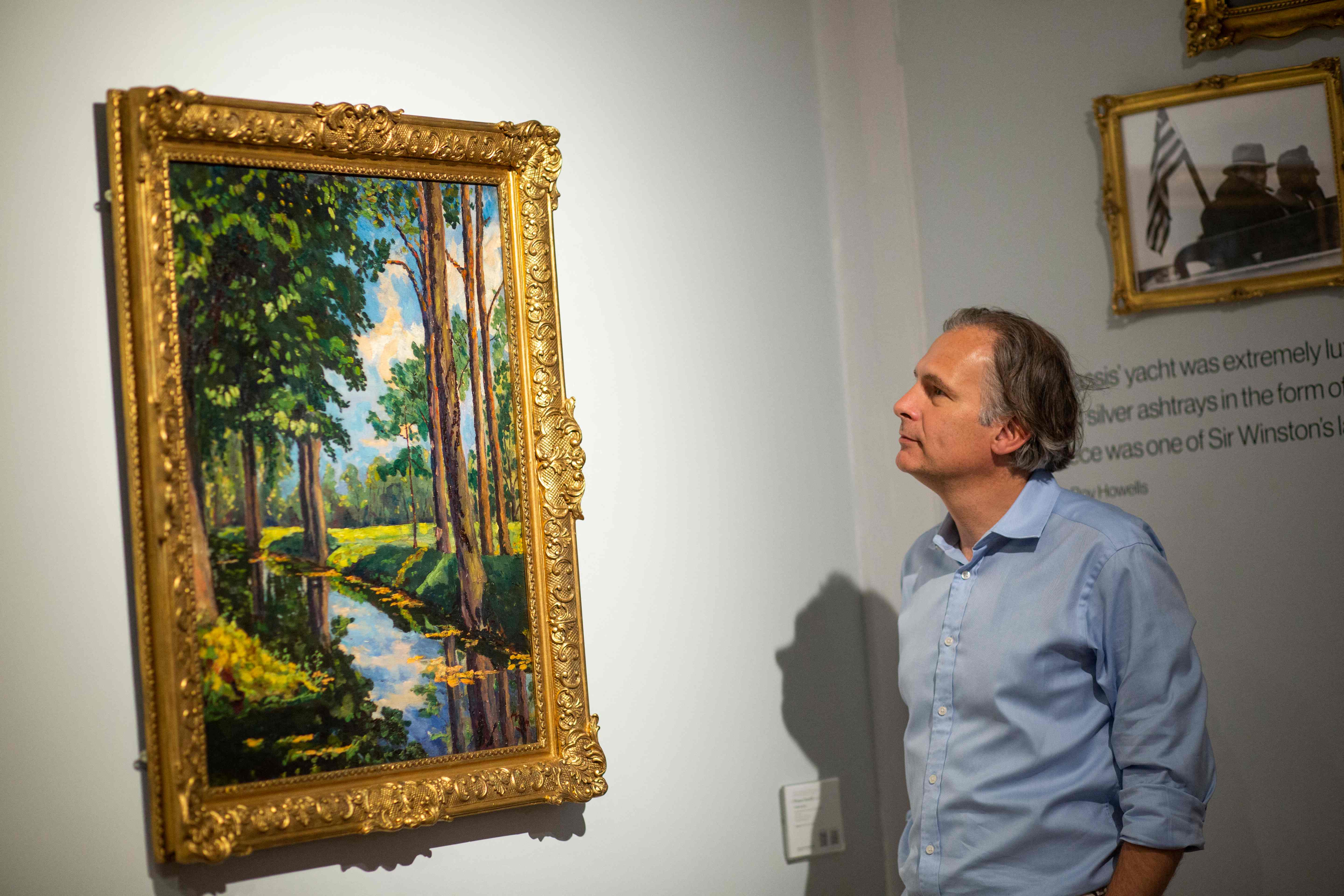 Seorang pengunjung melihat lukisan The Moat, Breccles karya Winston Churchill.