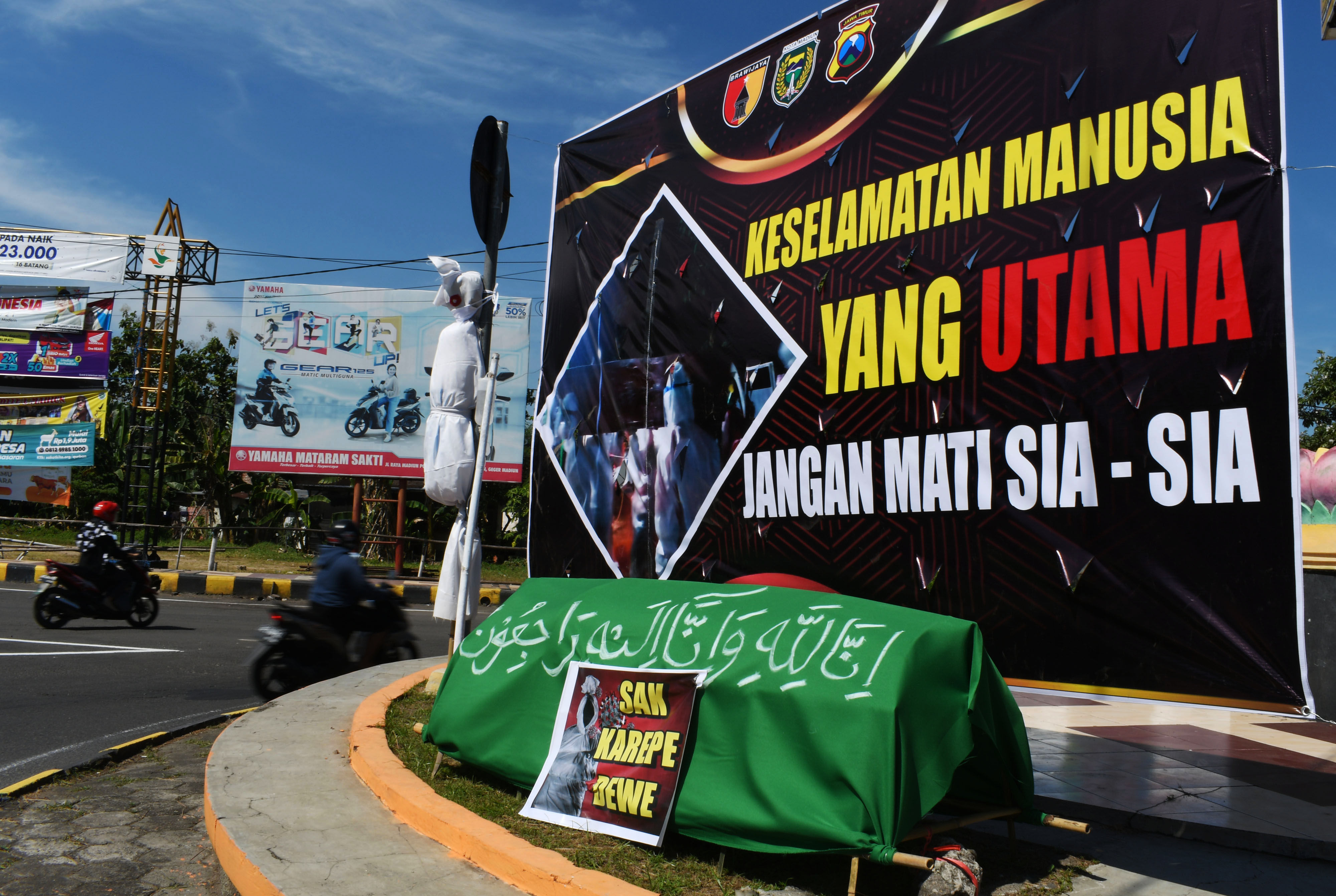 Pengendara melintasi spanduk kampanye bahaya covid-19 di wilayah Madiun, Jawa Timur.