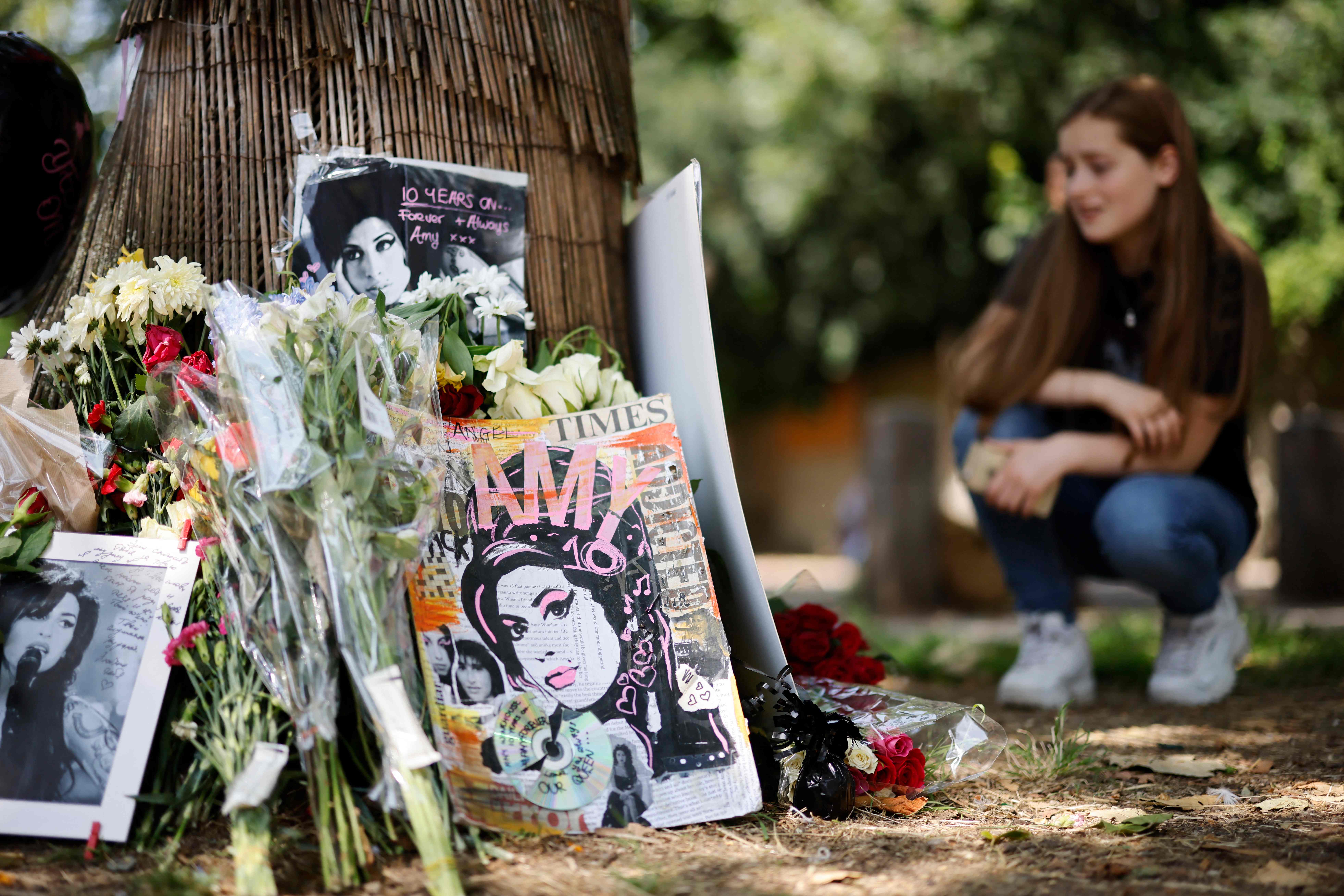 Seorang penggemar berlutut di dekat altar bagi mendiang musisi Amy Winehouse di London.