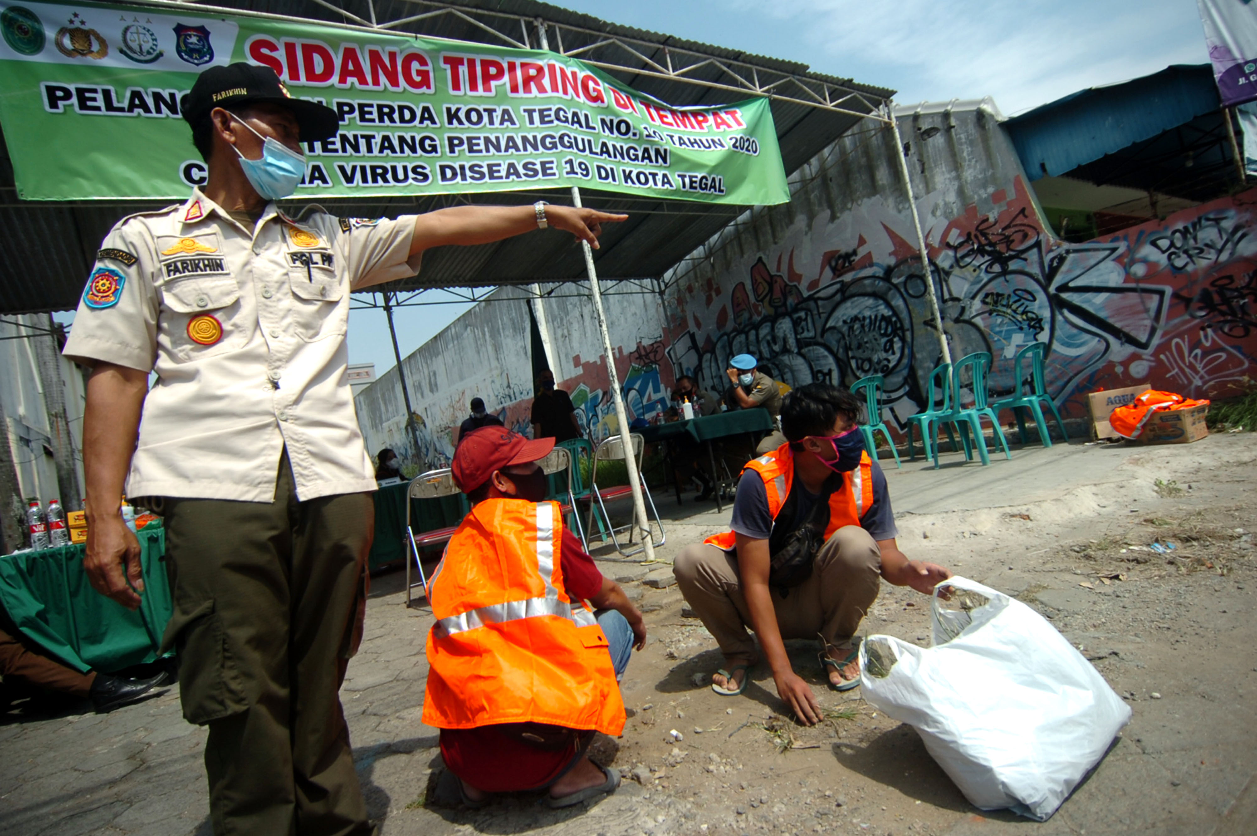 Pengendara yang tidak memakai masker menjalani hukuman sosial usai sidang prokes di Tegal.