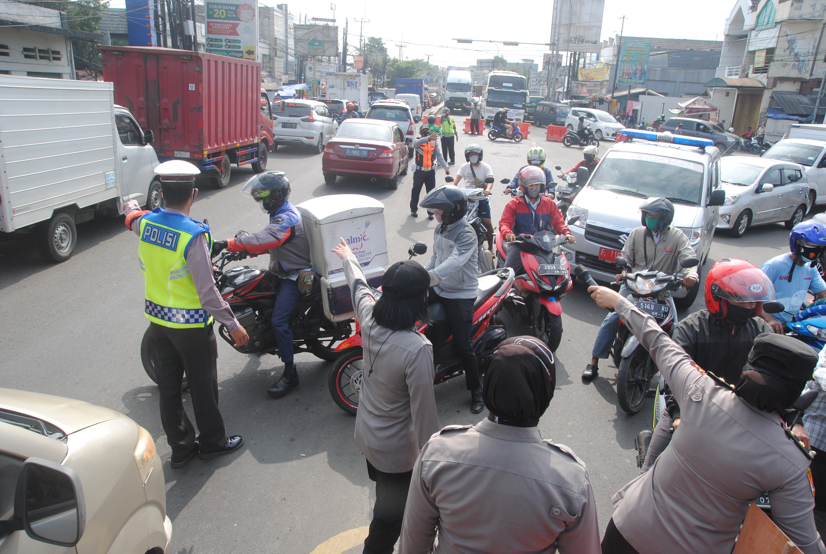 Anggota kepolisian mengarahkan pengendara untuk melalui jalan alternatif saat penyekatan.
