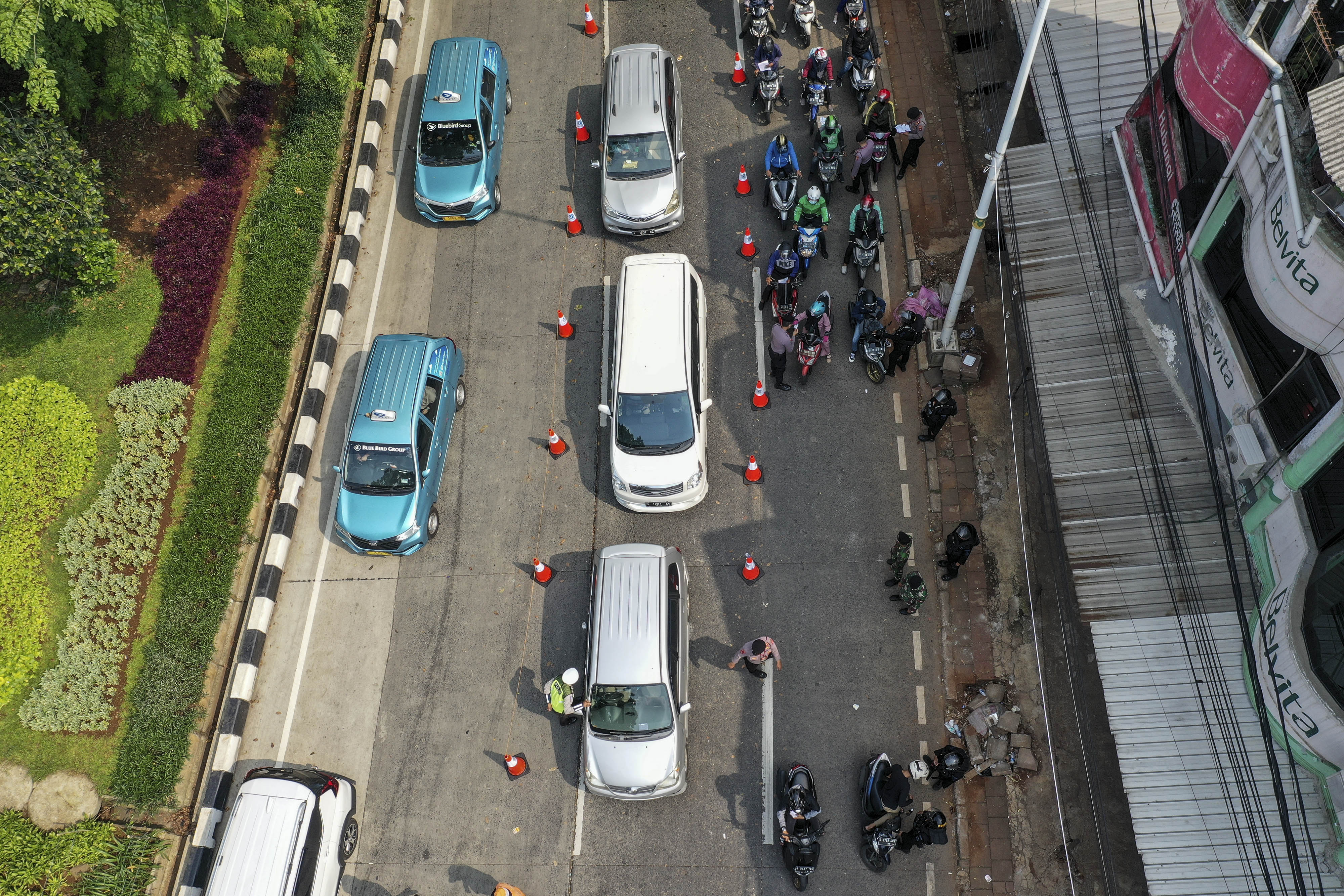 Petugas kepolisian memeriksa dokumen dan persyaratan pengendara yang melintasi pos penyekatan PPKM Darurat di Jalan Raya Lenteng Agung, Jaka