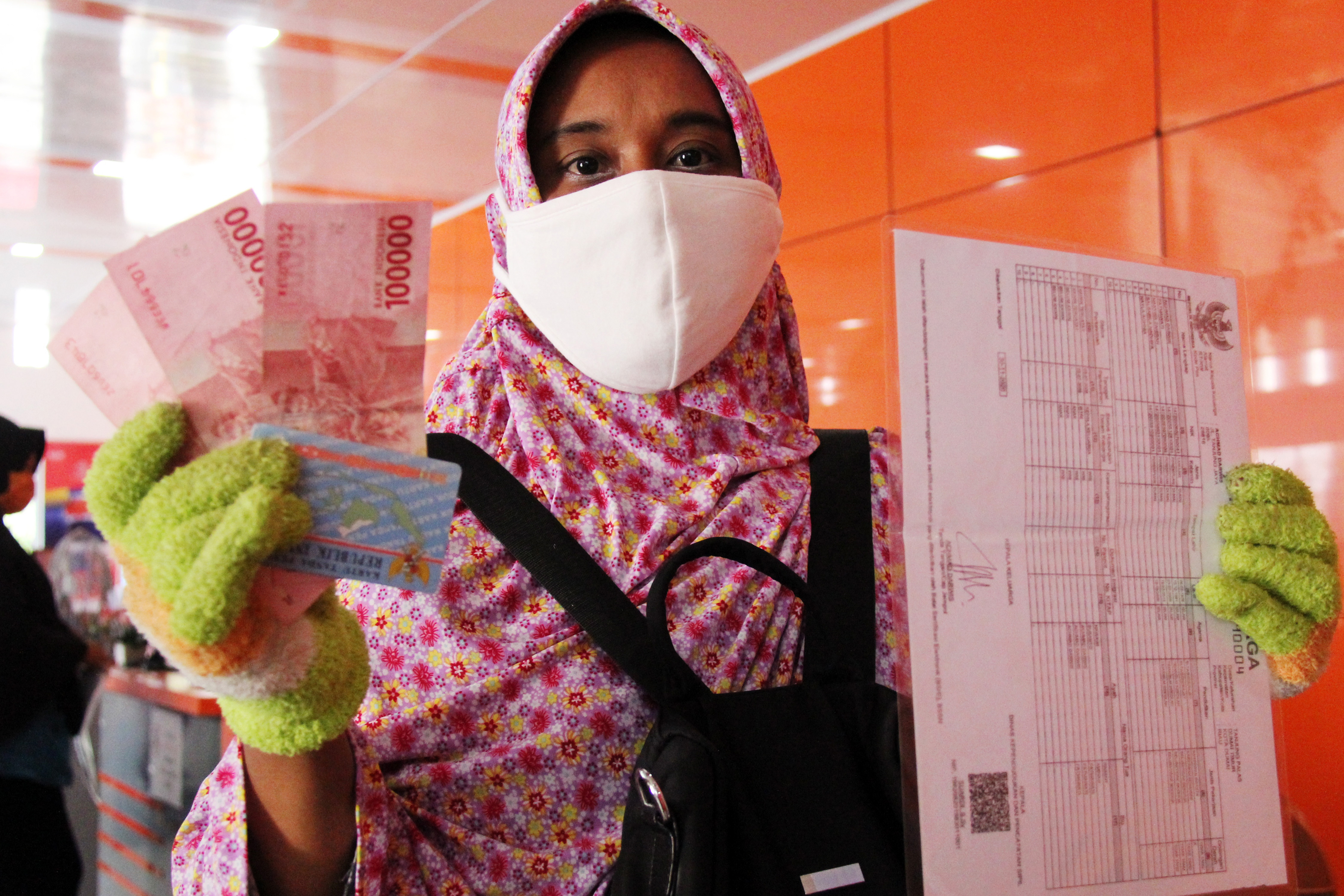 Warga menunjukkan uang bansos tunai di Kantor Pos Dumai, Riau.