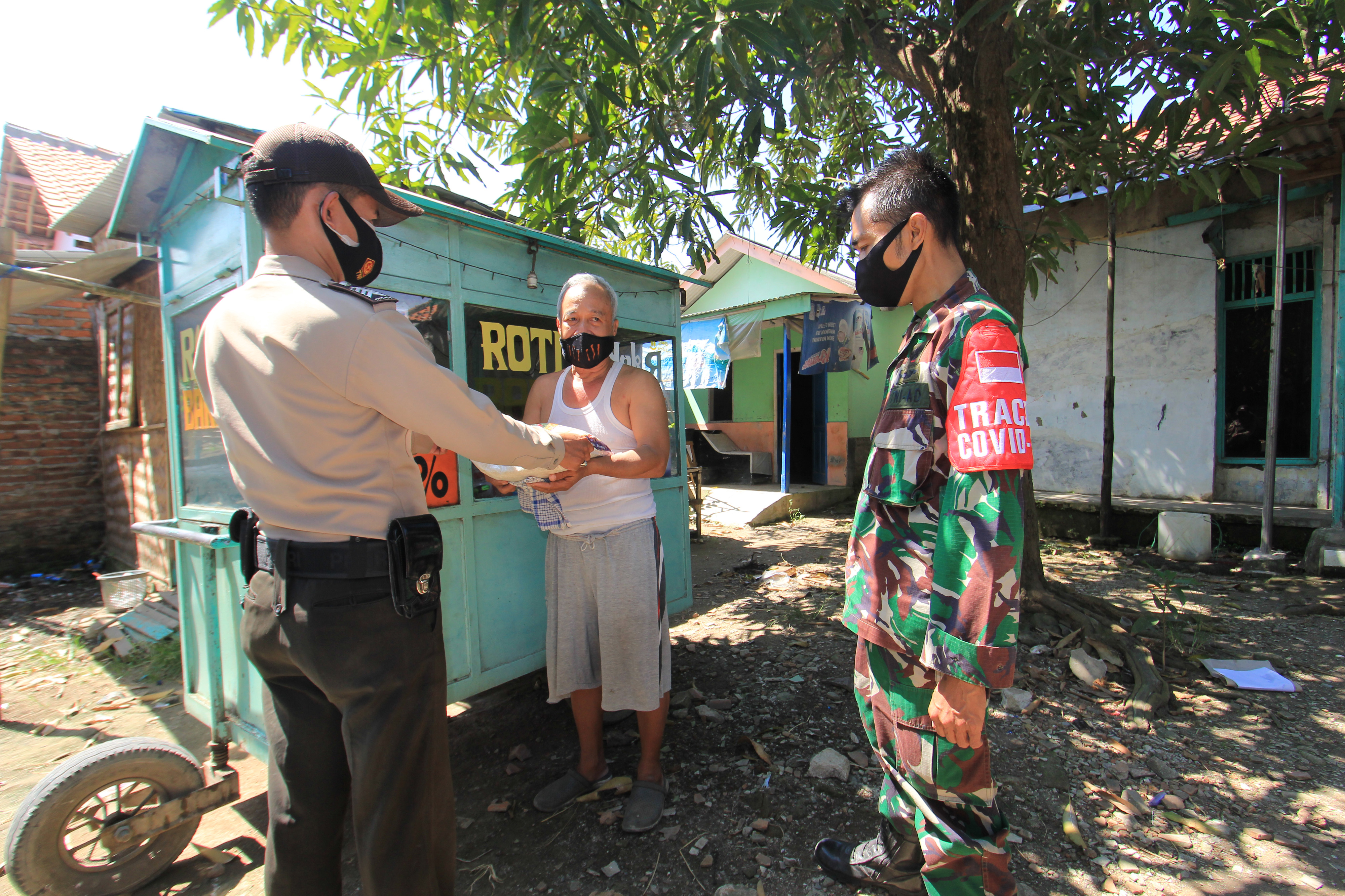 BANTUAN BERAS: Petugas dari Polri/TNI Karangampel memberikan bantuan beras kepada warga di desa Sendang, Indramayu, Jabar, Sabtu (17/72021).