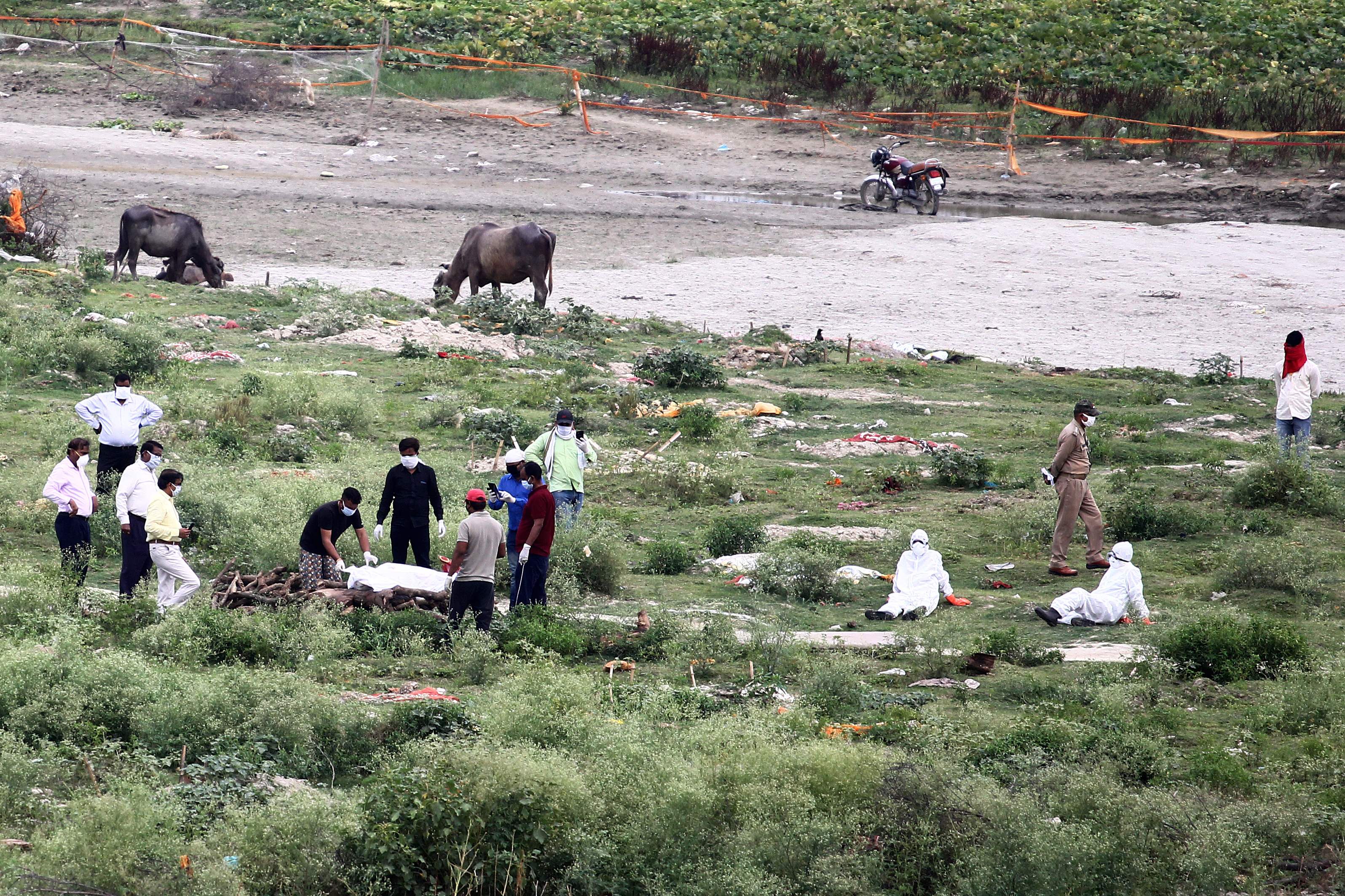 Petugas medis dan keluarga korban meninggal akibat Covid-19 mempersiapkan pemakamanan di dekat Sungai Gangga, Allahabad, India. 