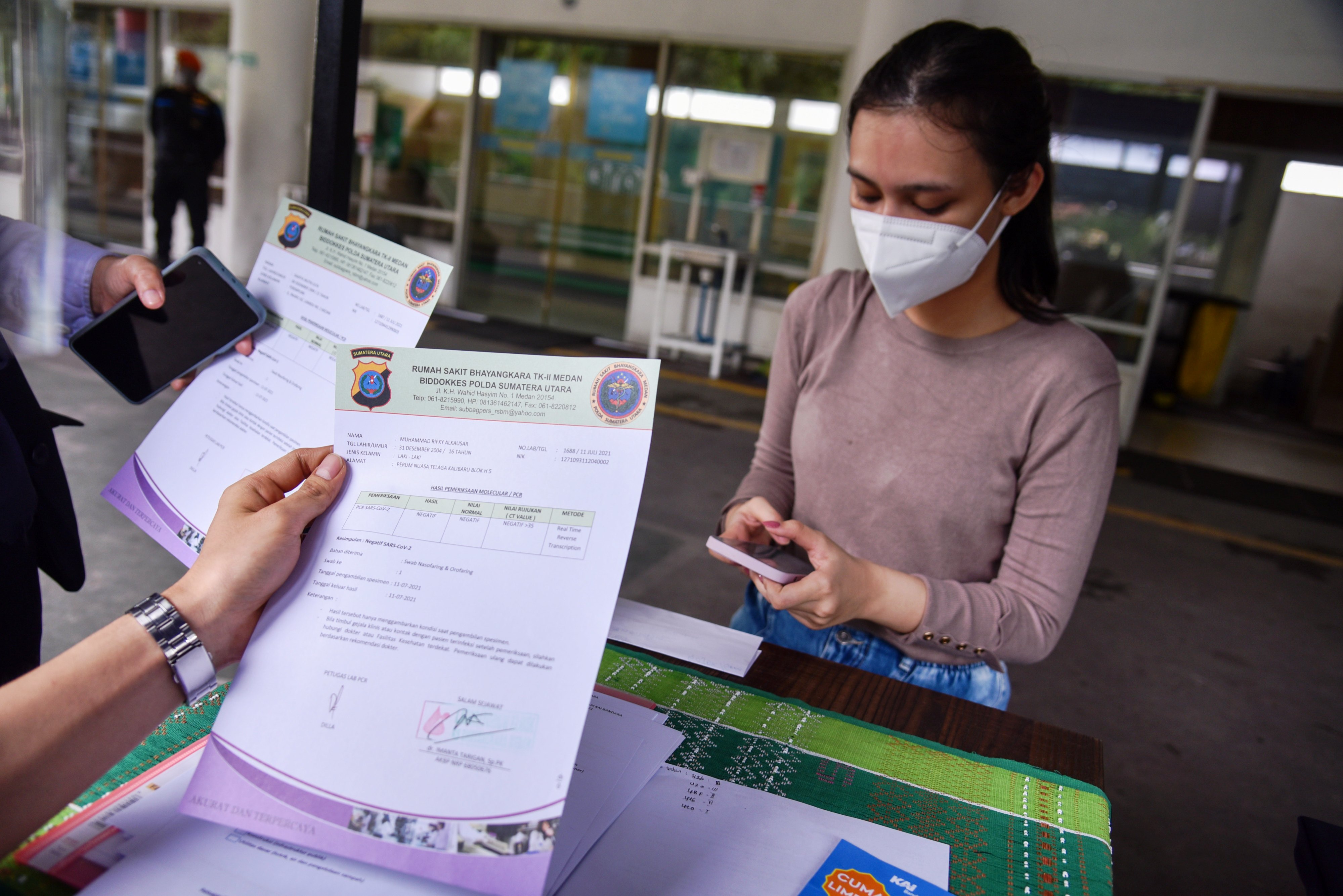 Petugas sedang memeriksa surat kelengkapan calon penumpang kereta.