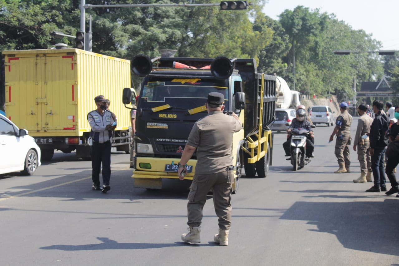 Petugas Satpol PP saat mengarahkan kendaraan untuk dilakukan pemeriksaan.