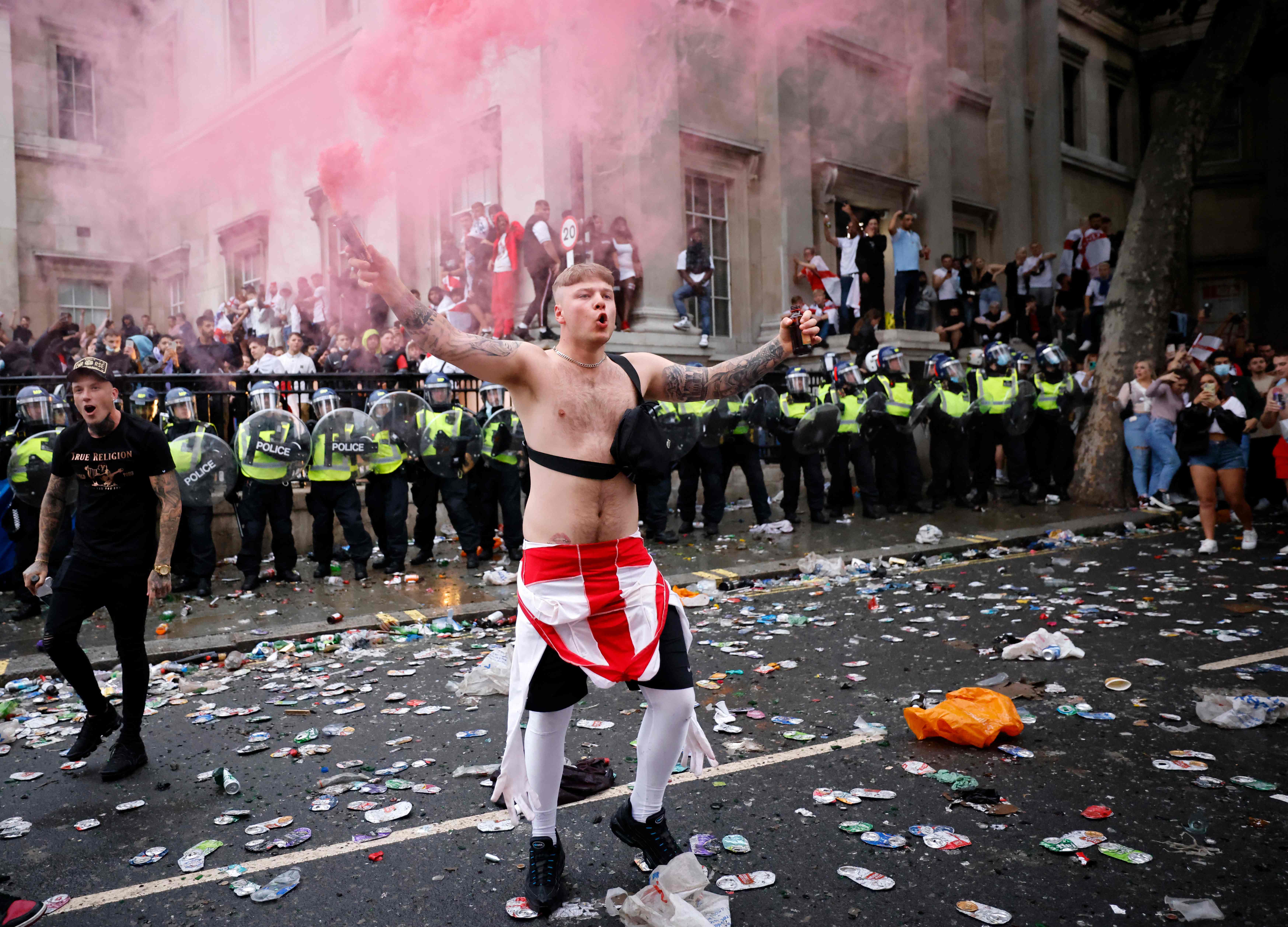 Seorang pendukung Inggris melambaikan bom asap di depan barisan polisi di Trafalgar Square saat laga final Piala Eropa 2020.