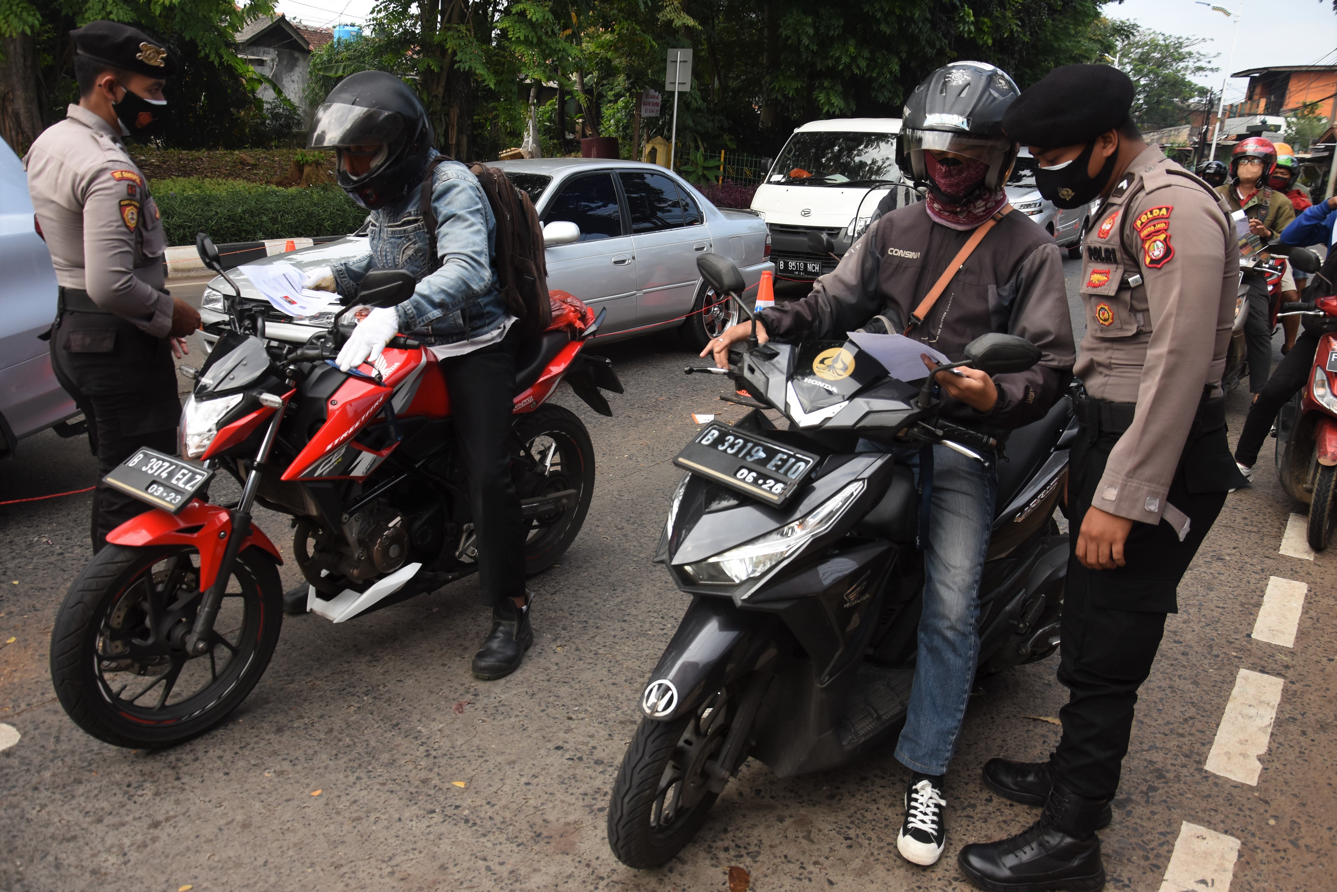Petugas gabungan memeriksa STRP milik pengendara di pos penyekatan PPKM Darurat.