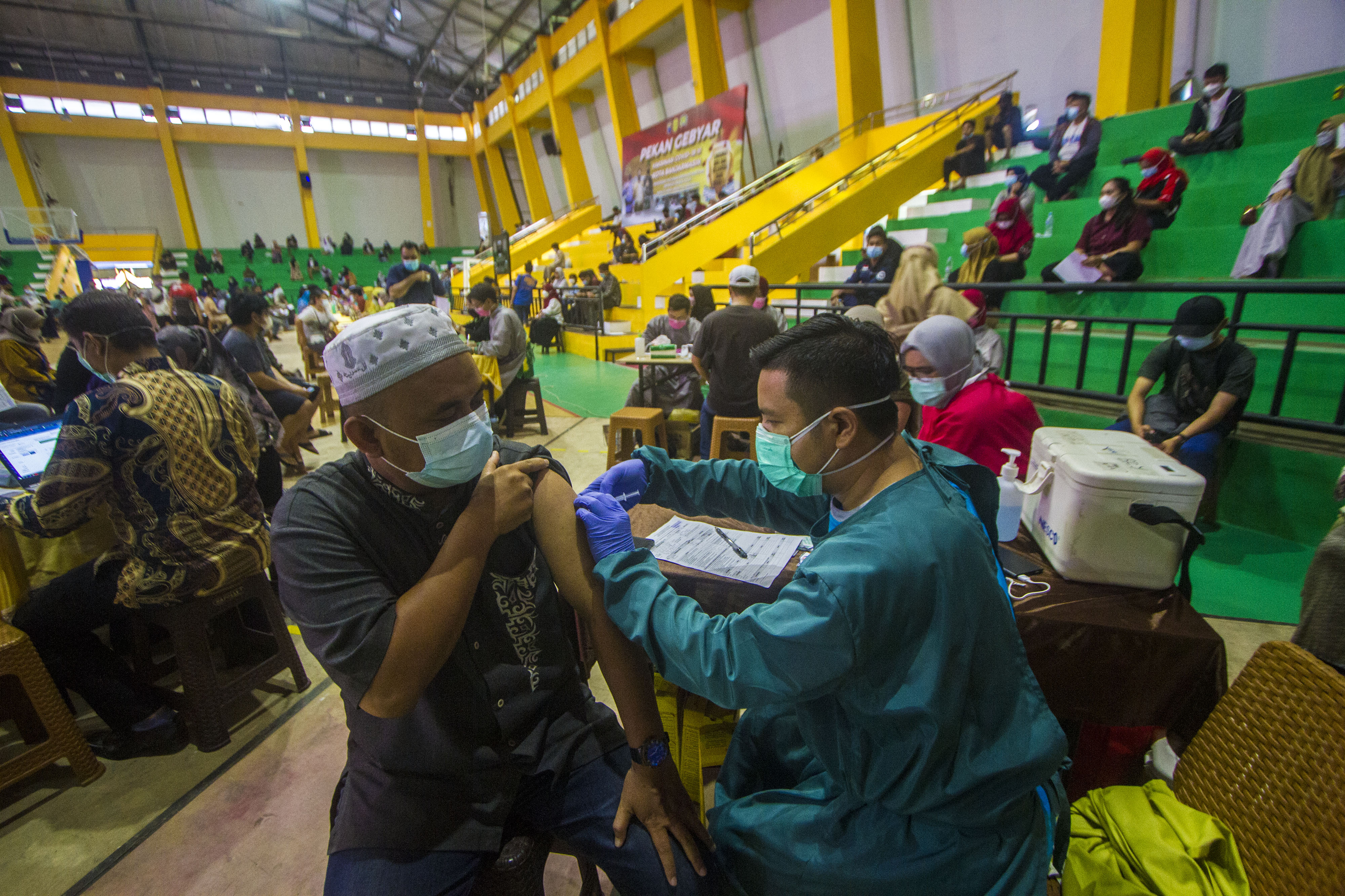  Petugas kesehatan menyuntikkan vaksin Covid-19 pada warga saat vaksinasi massal di GOR Hasanuddin HM, Banjarmasin, Kalimantan Selatan.