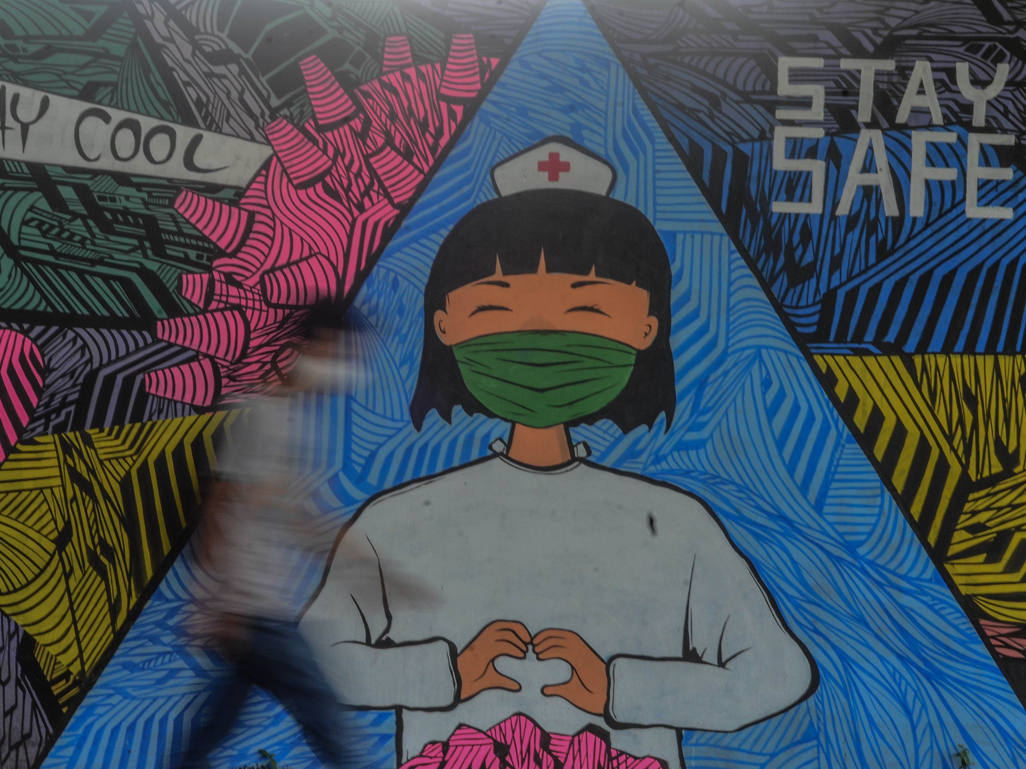 Warga melintas di depan mural tentang pandemi virus korona atau covid-19 di Kabupaten Ciamis, Jawa Barat.