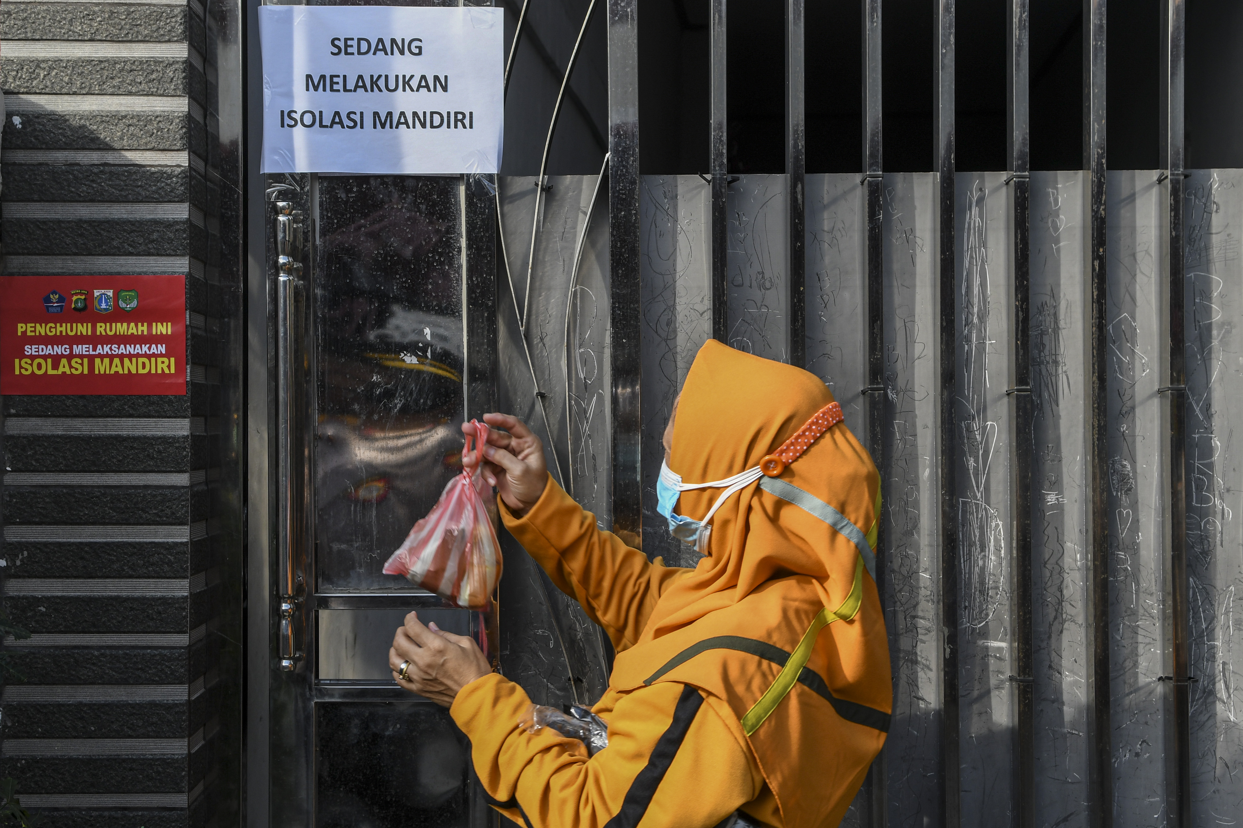 Petugas satgas covid-19 menggantungkan makanan di pagar rumah warga yang menjalani isolasi mandiri.