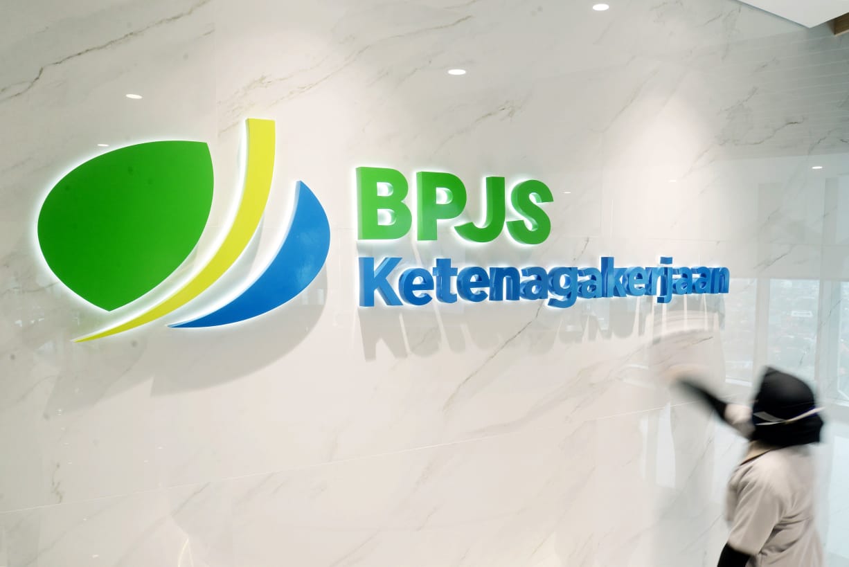 Pekerja membersihkan tembok dengan terpampang logo BPJS Ketenagakerjaan di Gedung BPJAMSOSTEK, Jakarta. 