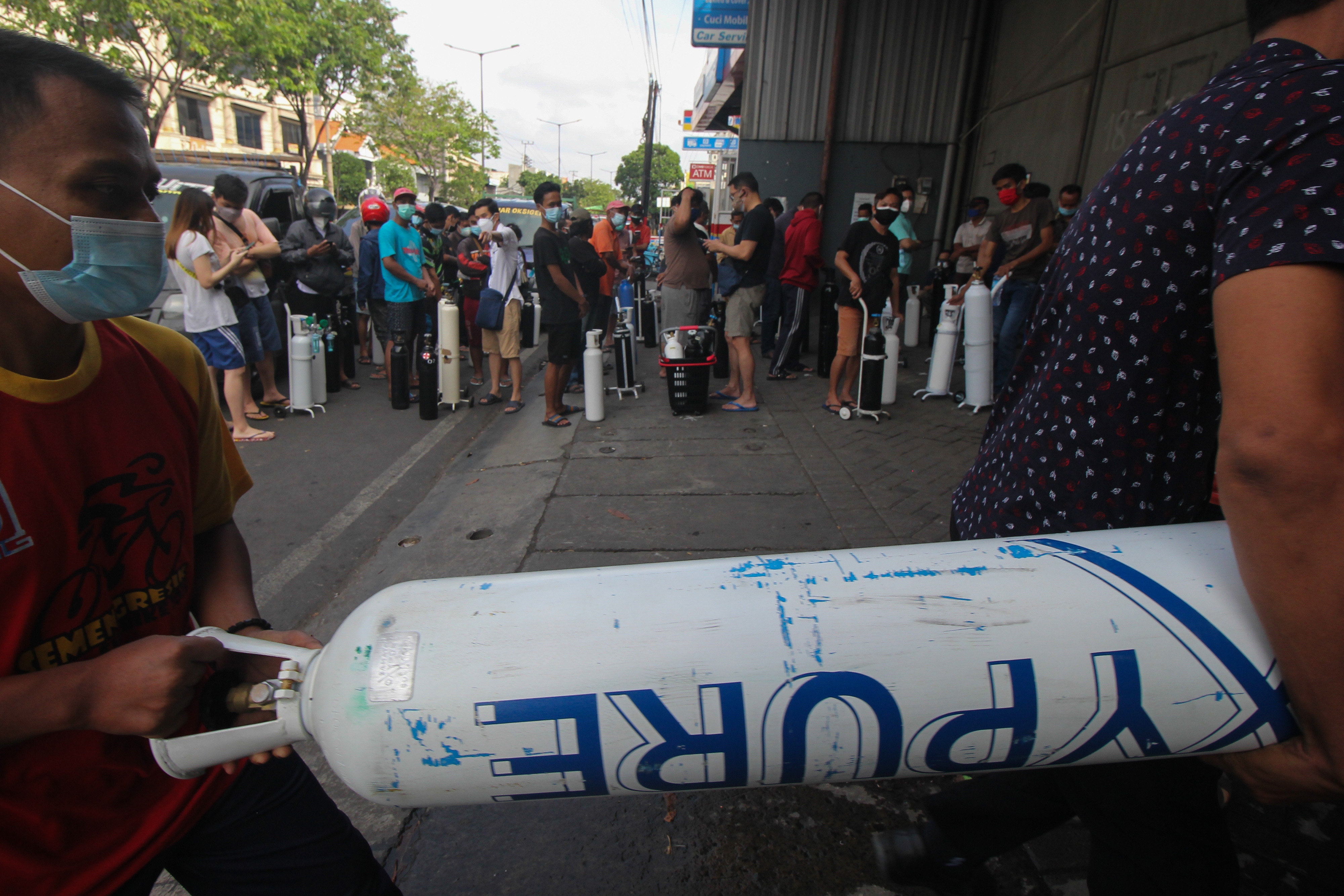 Warga antre untuk mengisi ulang oksigen di agen pengisian oksigen di Jalan Kenjeran, Surabaya, Jawa Timur, Senin (12/7/2021)
