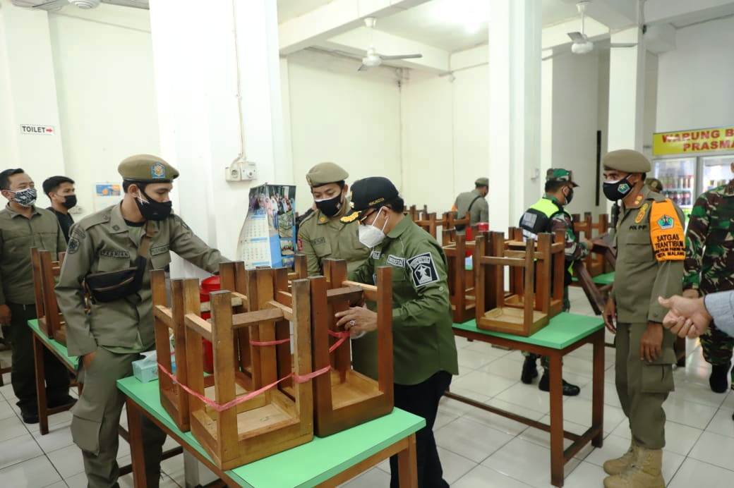 Petugas Satuan Polisi Pamong Praja Kota Malang, Jawa Timur, mengikat kursi sebuah kedai makanan, Selasa (6/7) malam. 