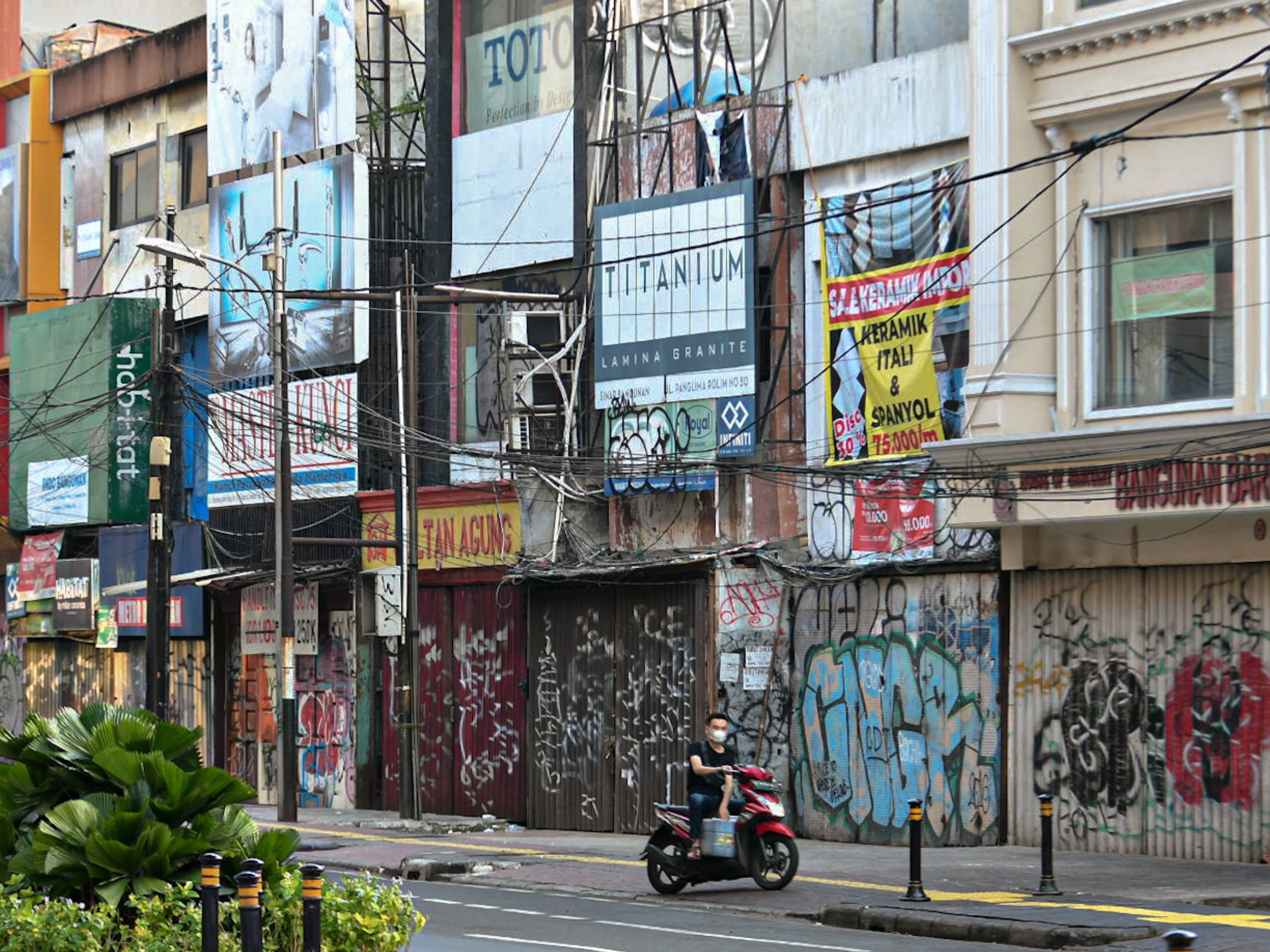 Warga melintas di dekat ruko yang tutup di Jalan RS Fatmawati Raya, Jakarta, Minggu (18/7).