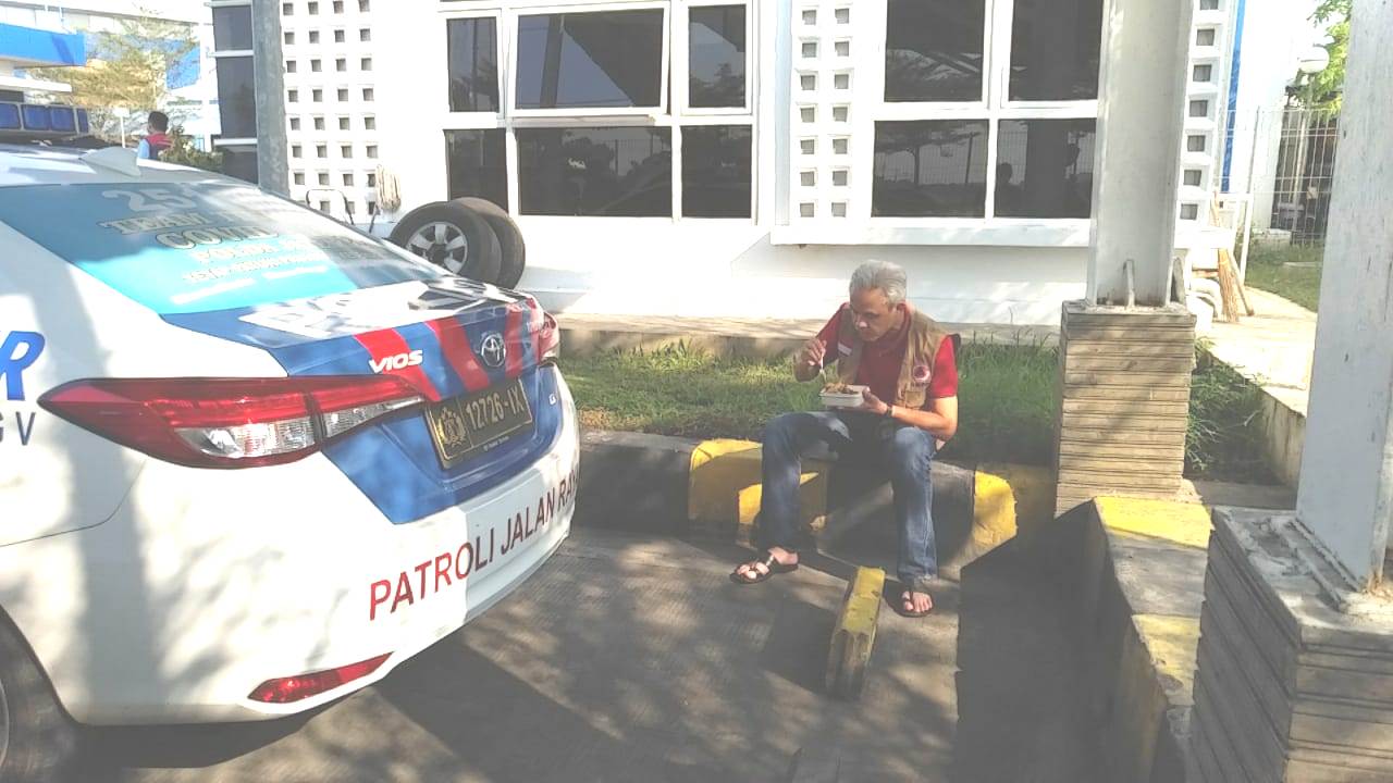 Gubernur Jateng Ganjar Pranowo sedang menyantap makan dari dari nasi kotak saat istirahat di dekat pintu masuk tol Pemalang, Minggu (4/7).