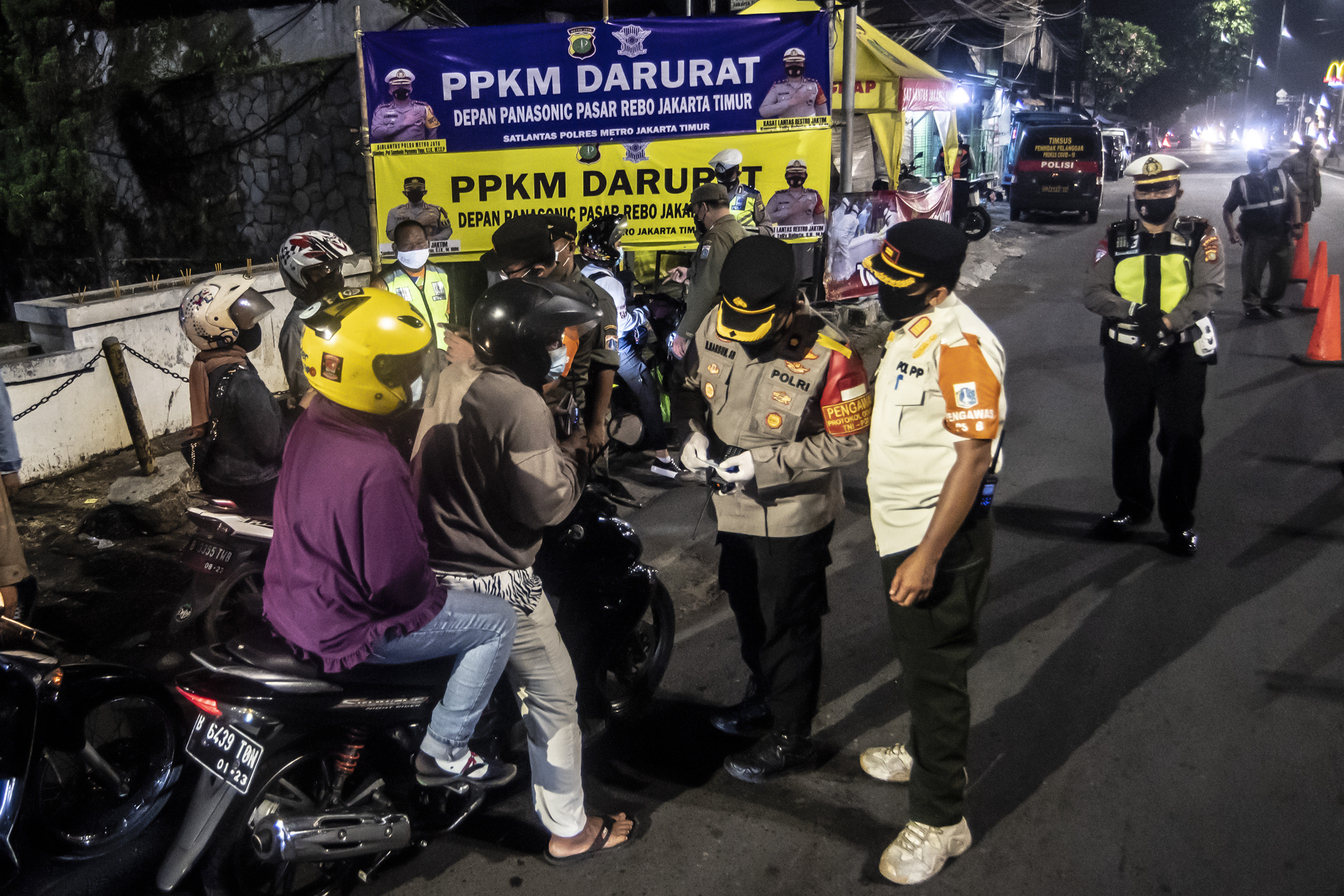 Petugas memeriksa identitas pengendara sepeda motor dalam rangka PPKM Darurat di Jalan Raya Bogor, Jakarta, Jumat (2/7).
