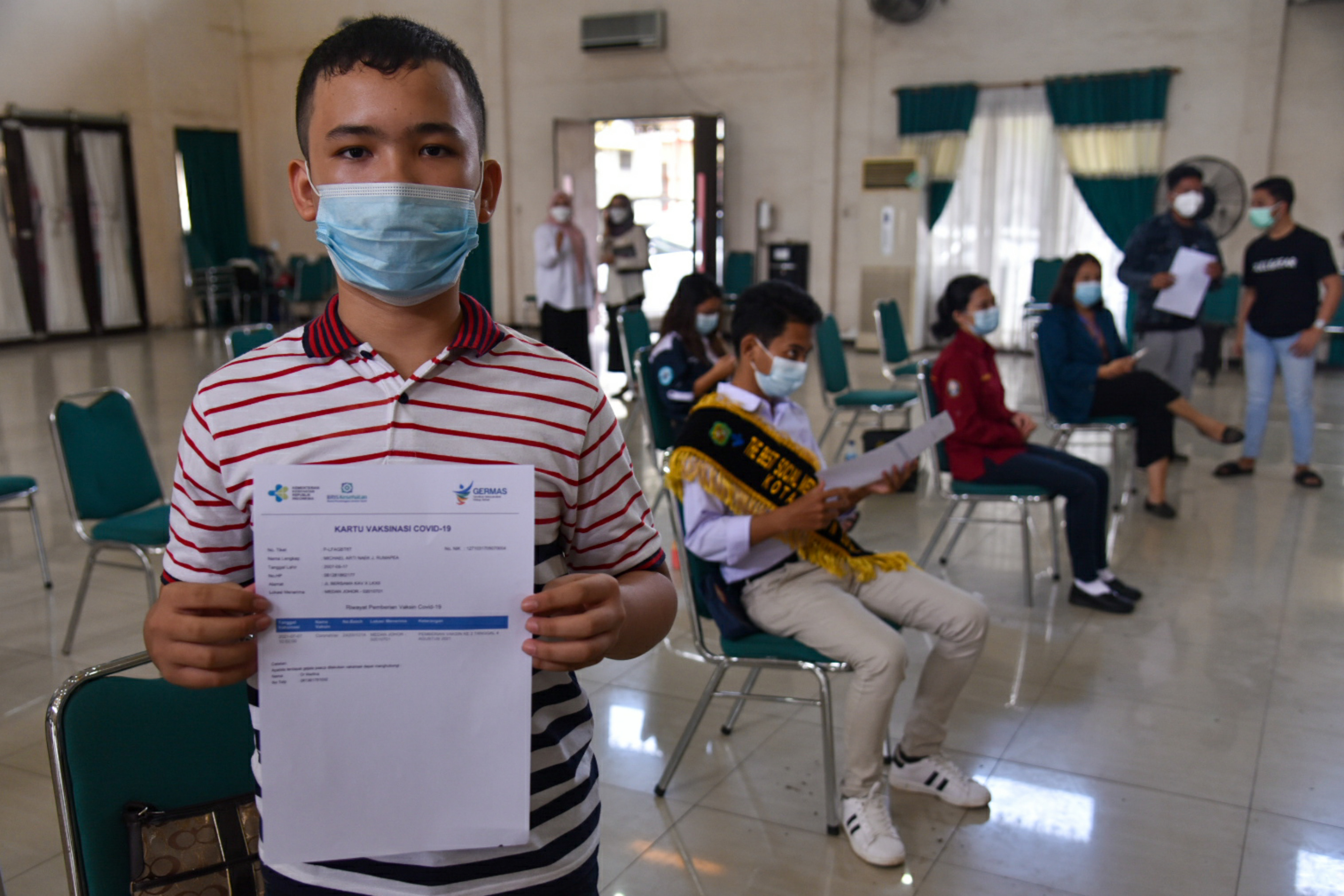 Seorang anak penerima vaksin covid-19 menunjukan sertifikat vaksin di Gedung PKK, Medan Petisah, Kota Medan, Rabu (7/7/2021).