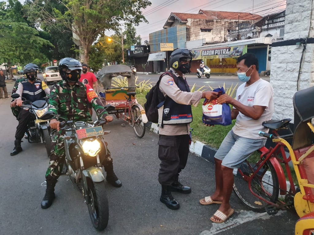 Personel kepolisian dan TNI membagikan bansos kepada warga di Solo.