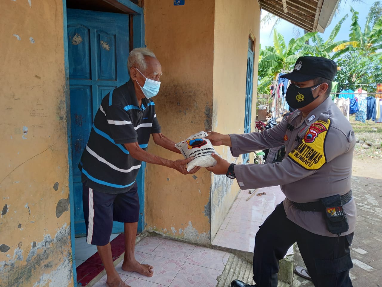 Personel Polres Brebes sedang memberikan bantuan beras kepada warga.