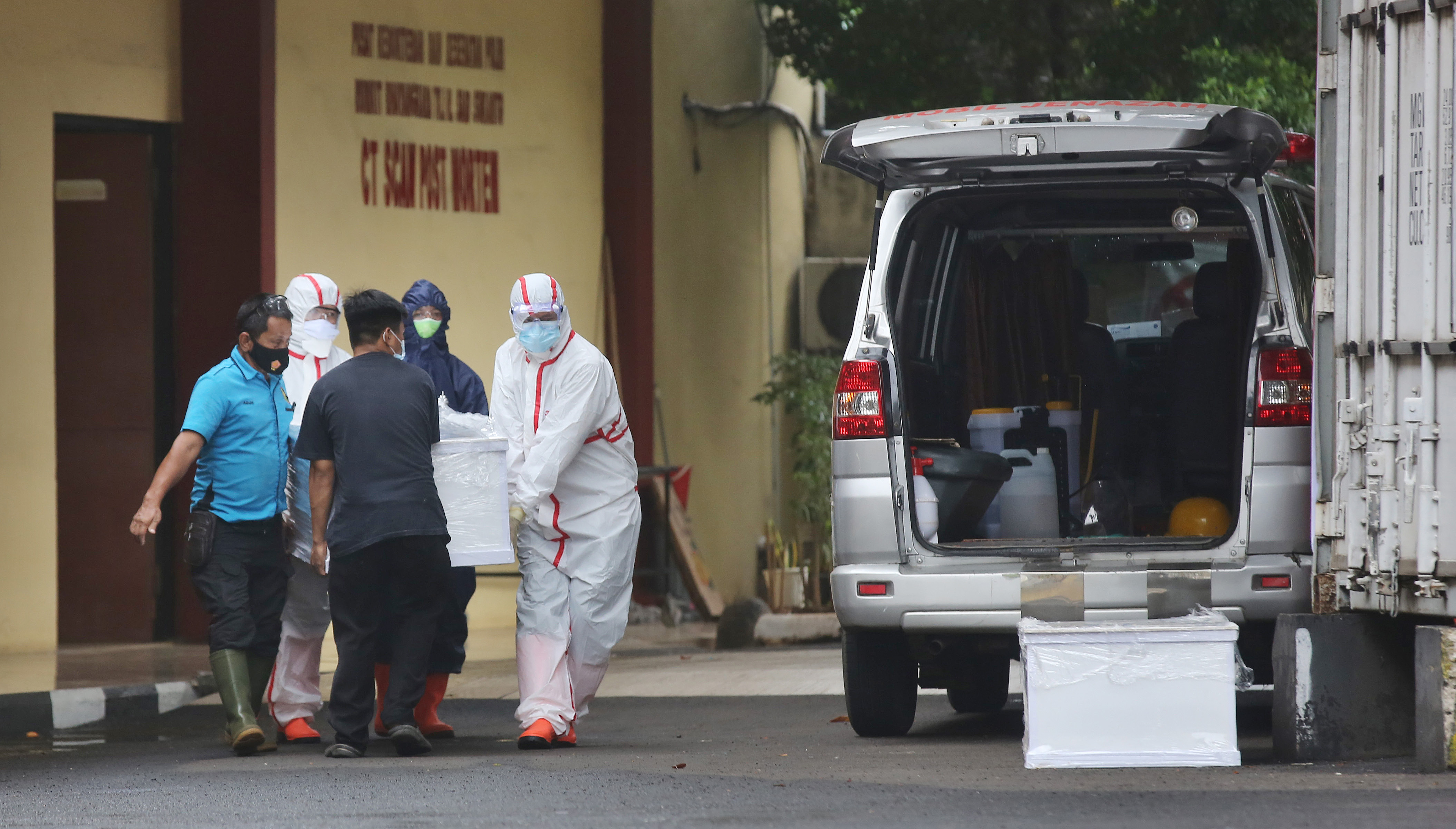 Petugas pemulasaraan mengangkat peti mati jenazah terkonfirmasi positif covid-19 di RS Polri, Kramat Jati, Jakarta,  Selasa (12/1/2020)