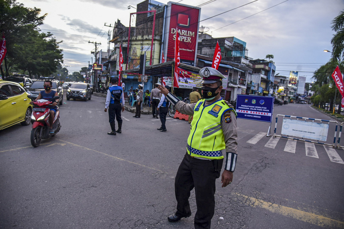 Seorang polisi mengatur lalu lintas di Kota Medan, Sumut saat dilakukan penyekaran dalam masa PPKM Darurat. 