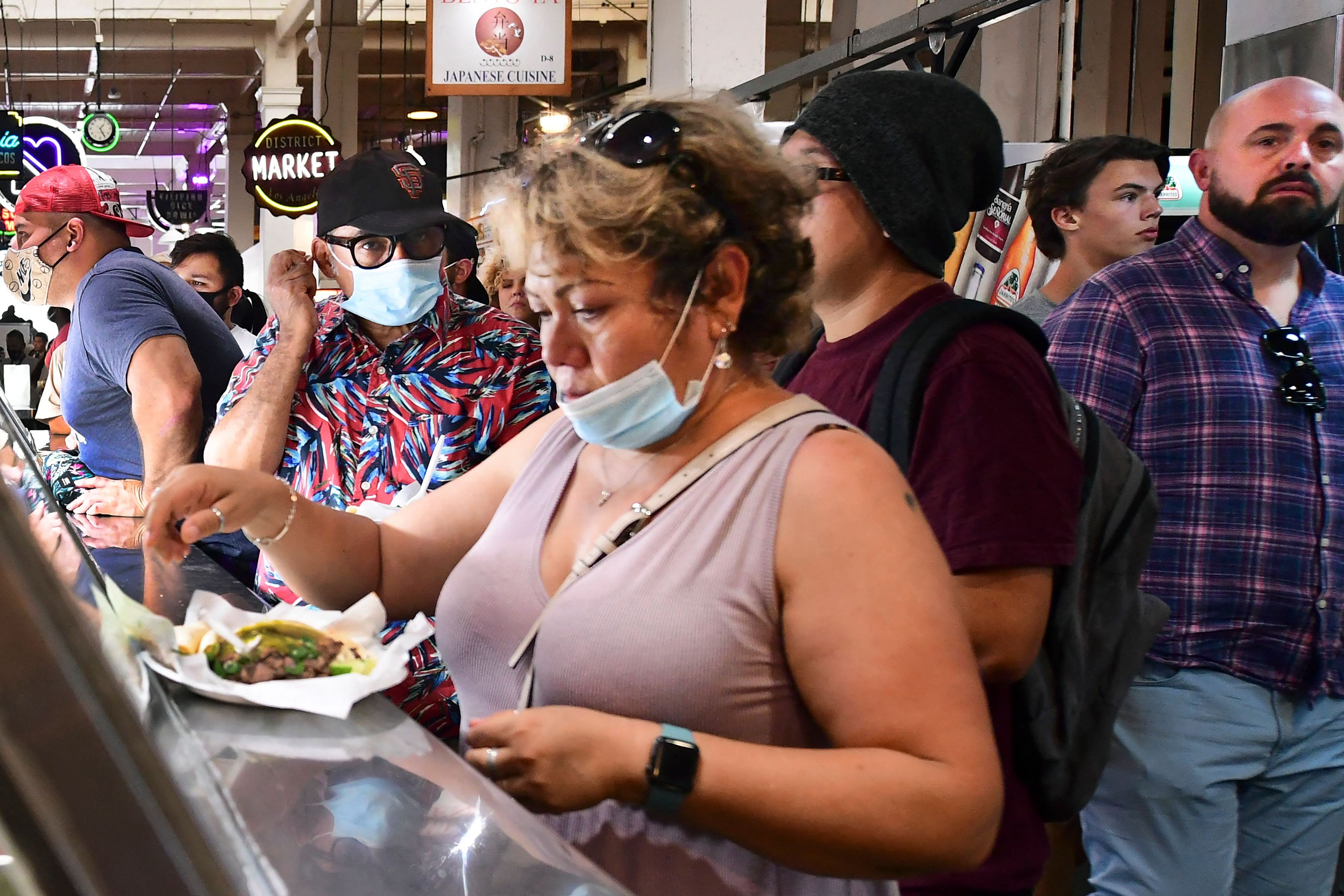Orang-orang bermasker dan tidak tengah berjalan melalui Grand Central Market di Los Angeles, California, pada 29 Juni 2021.