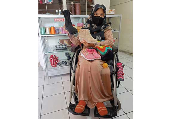 Penyandang disabilitas Silvia memperlihatkan contoh produk dari usaha yang digelutinya dengan menghasilkan tas rajutan dan sepatu rajutan.