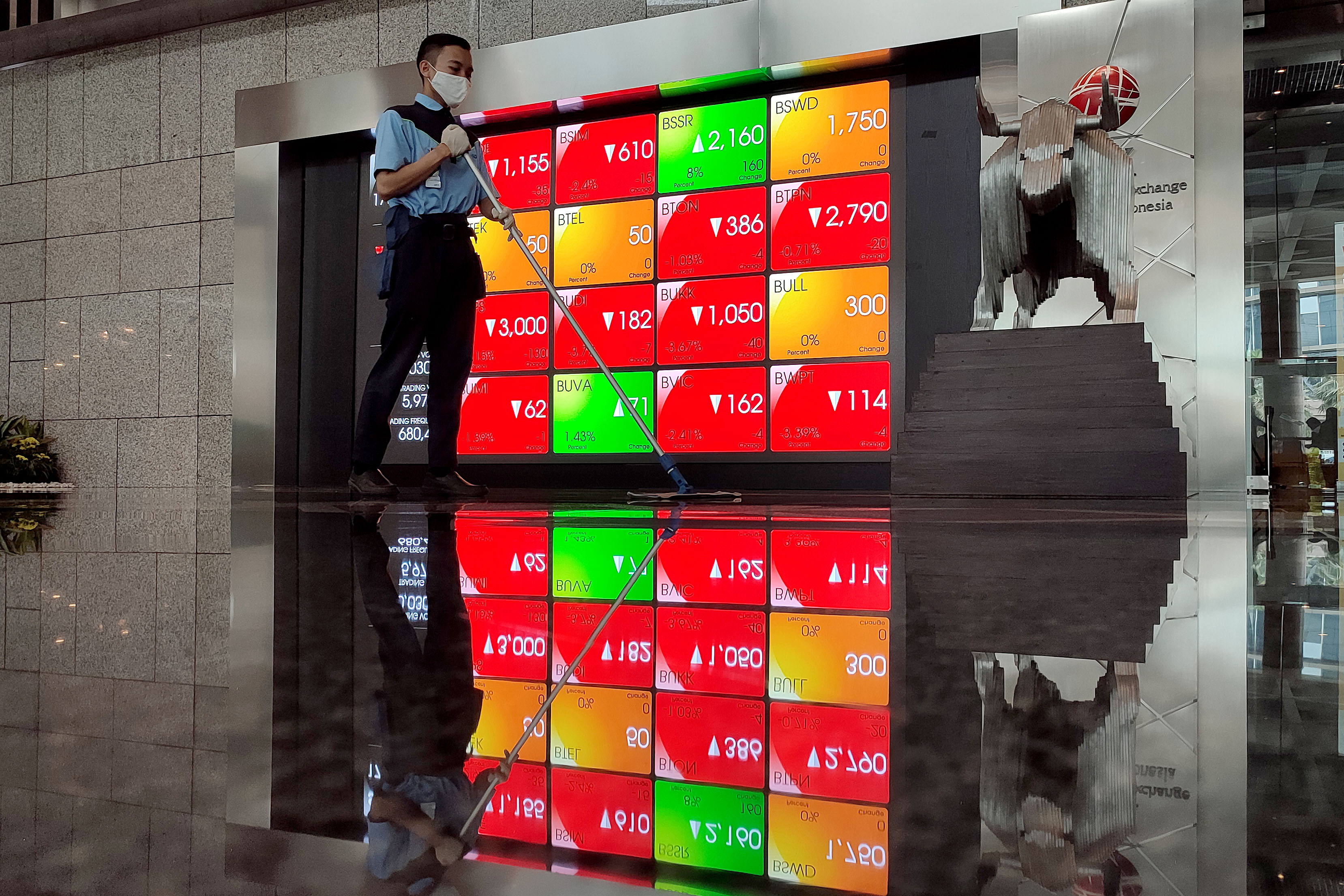  Pekerja melintas di depan papan elektronik yang menampilkan pergerakan Indeks Harga Saham Gabungan (IHSG) di Bursa Efek Indonesia, Jakarta.