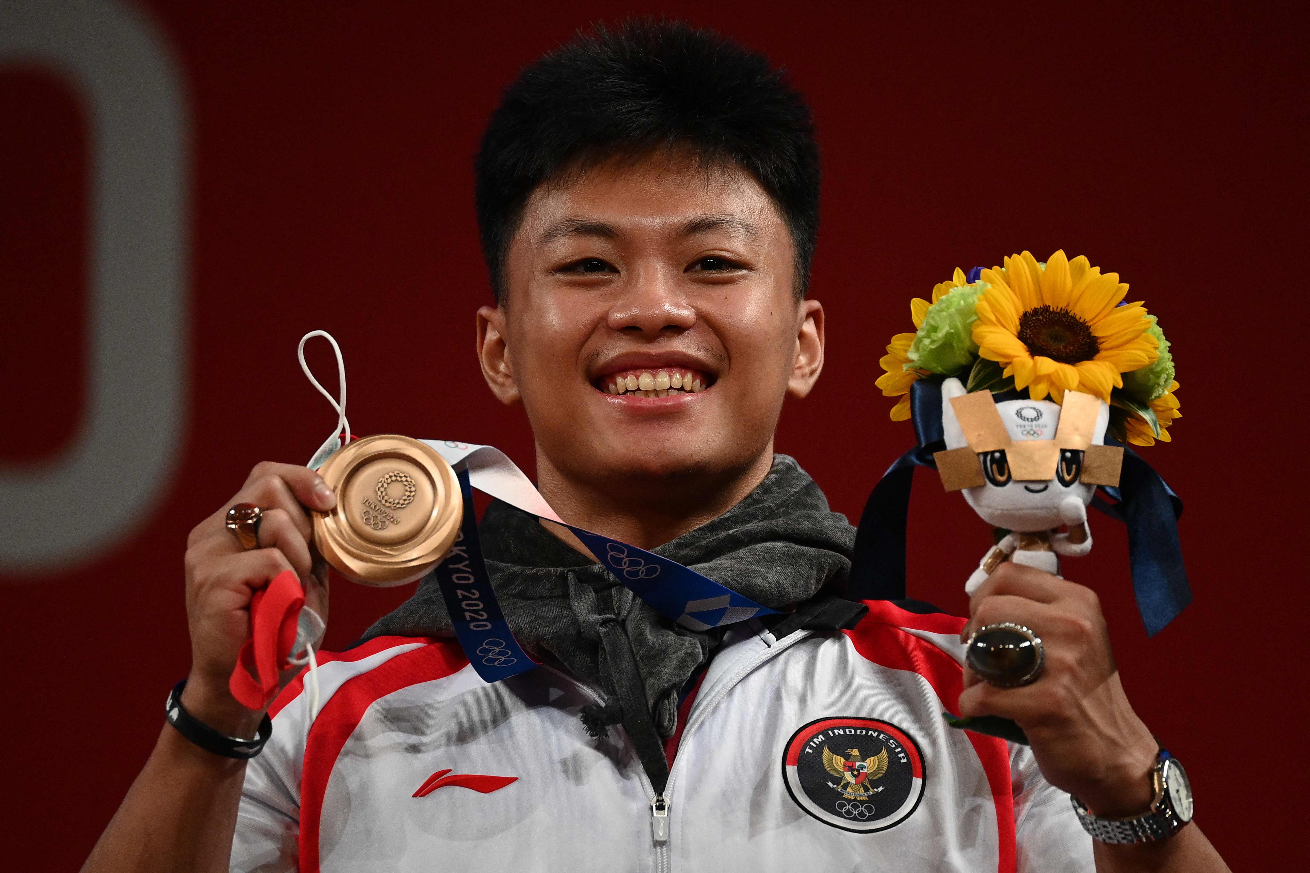 Lifter Indonesia Rahmat Erwin Abdullah menunjukkan medali perunggunya di ajang angkat berat kelas 73 kg di Olimpiade Tokyo 2020. 